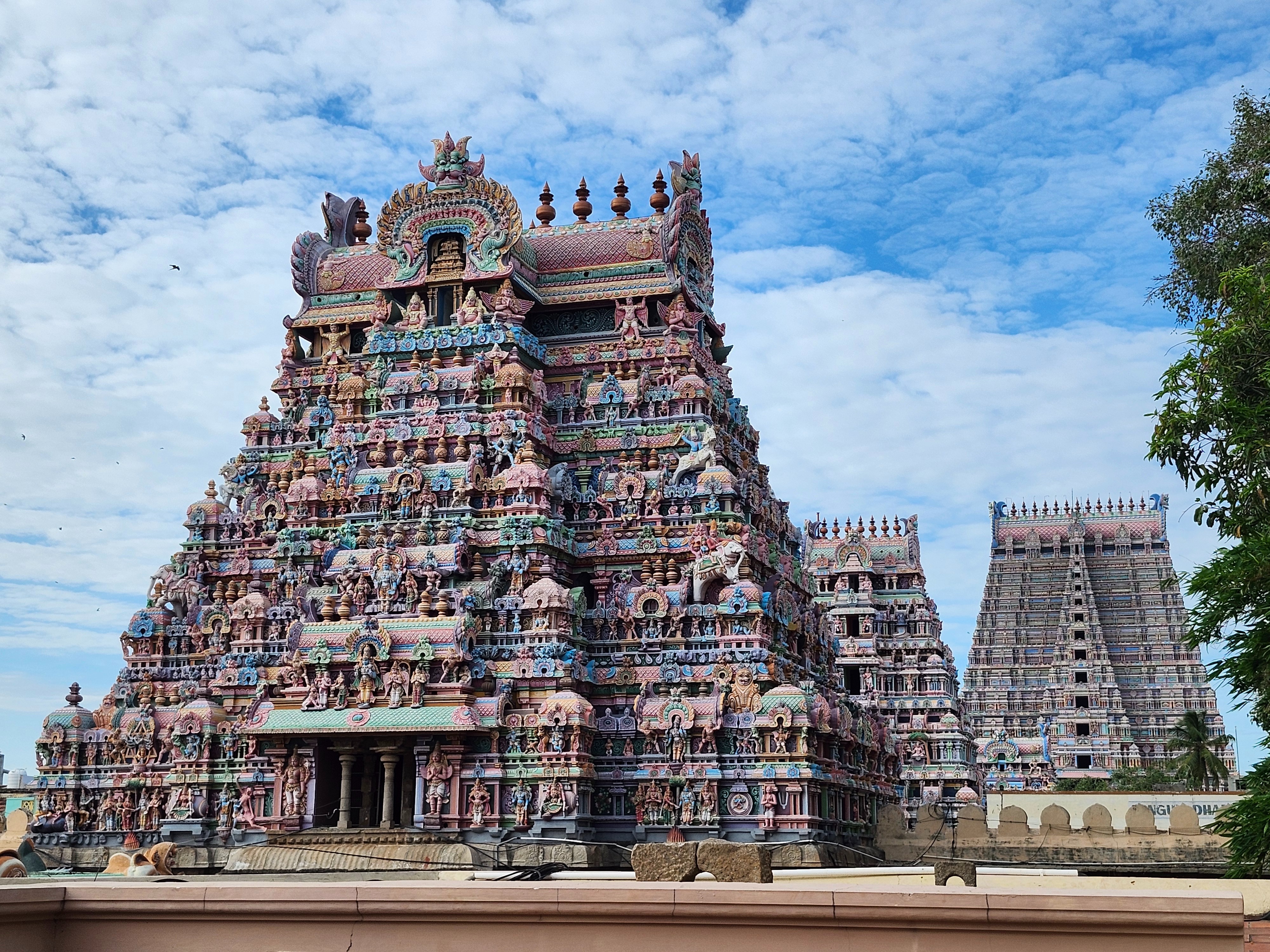 A vibrant Hindu temple adorned with intricate carvings and statues stands majestically under a blue sky.