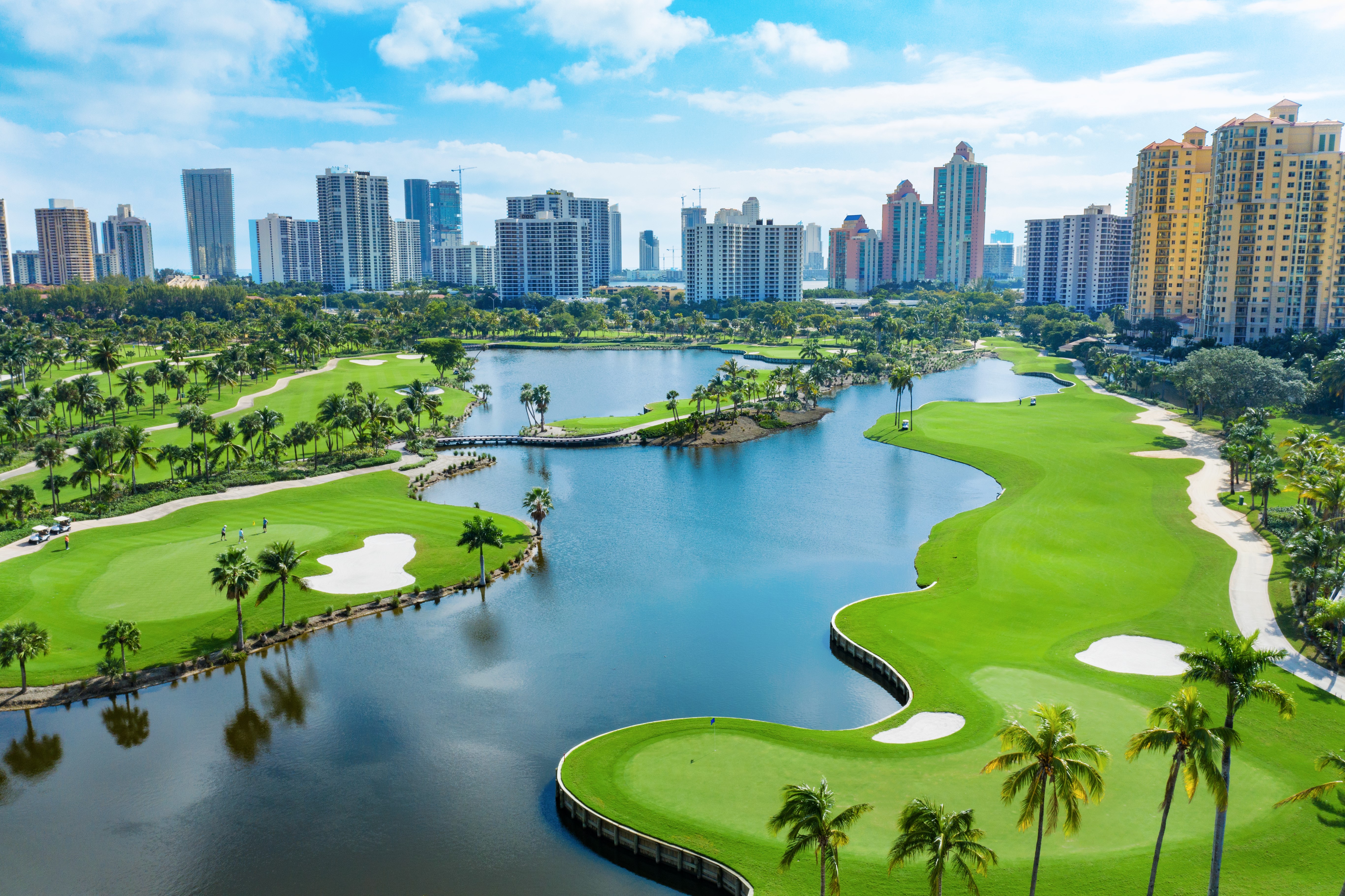 Aerial view of a large gold course the city buildings in the distance