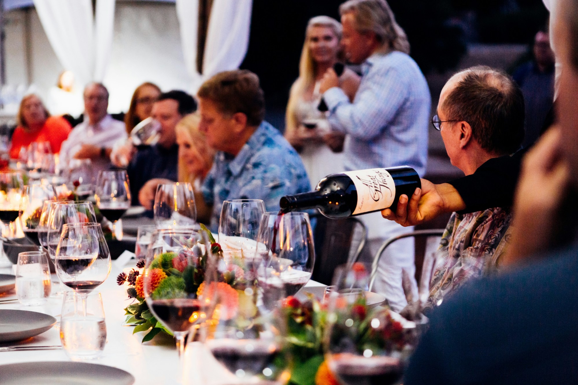 People sitting around table with wine glasses and wine bottle.