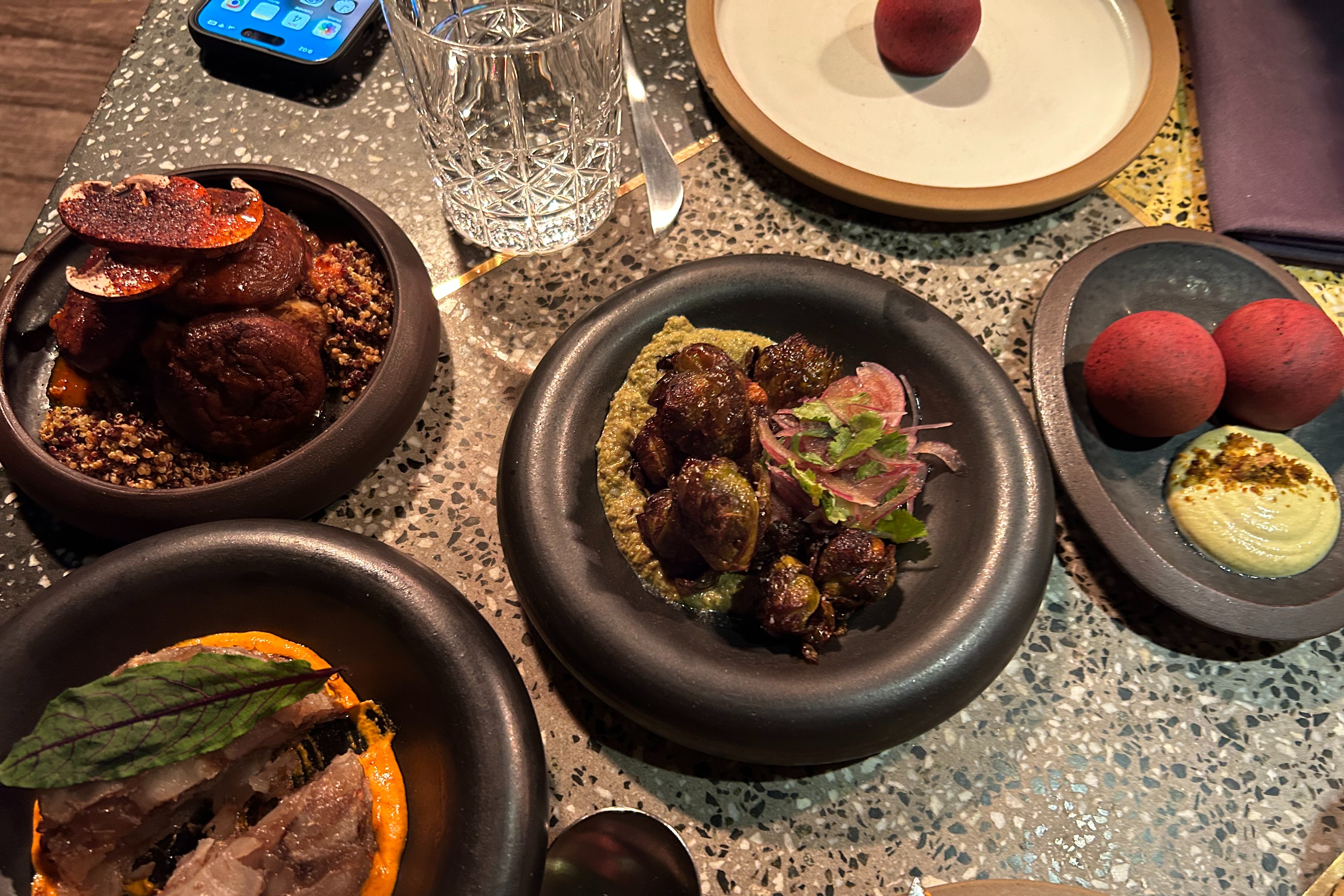 “Plant-based” cuisine served in small plates at Sacro on a brightly-li table.