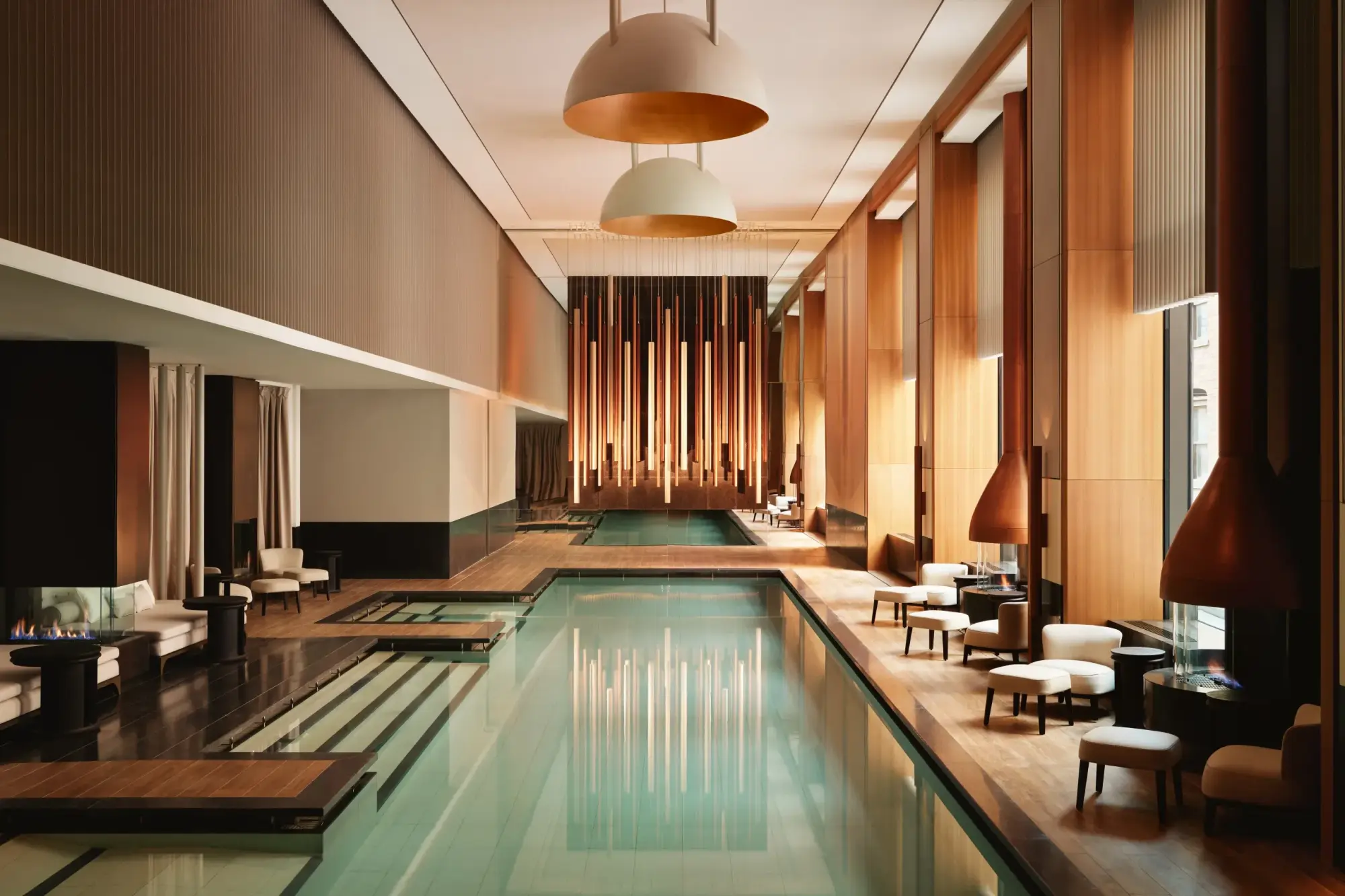 Indoor pool surrounded by chic loungers and seating. Neutral tones and stylish decor create a luxurious and tranquil setting