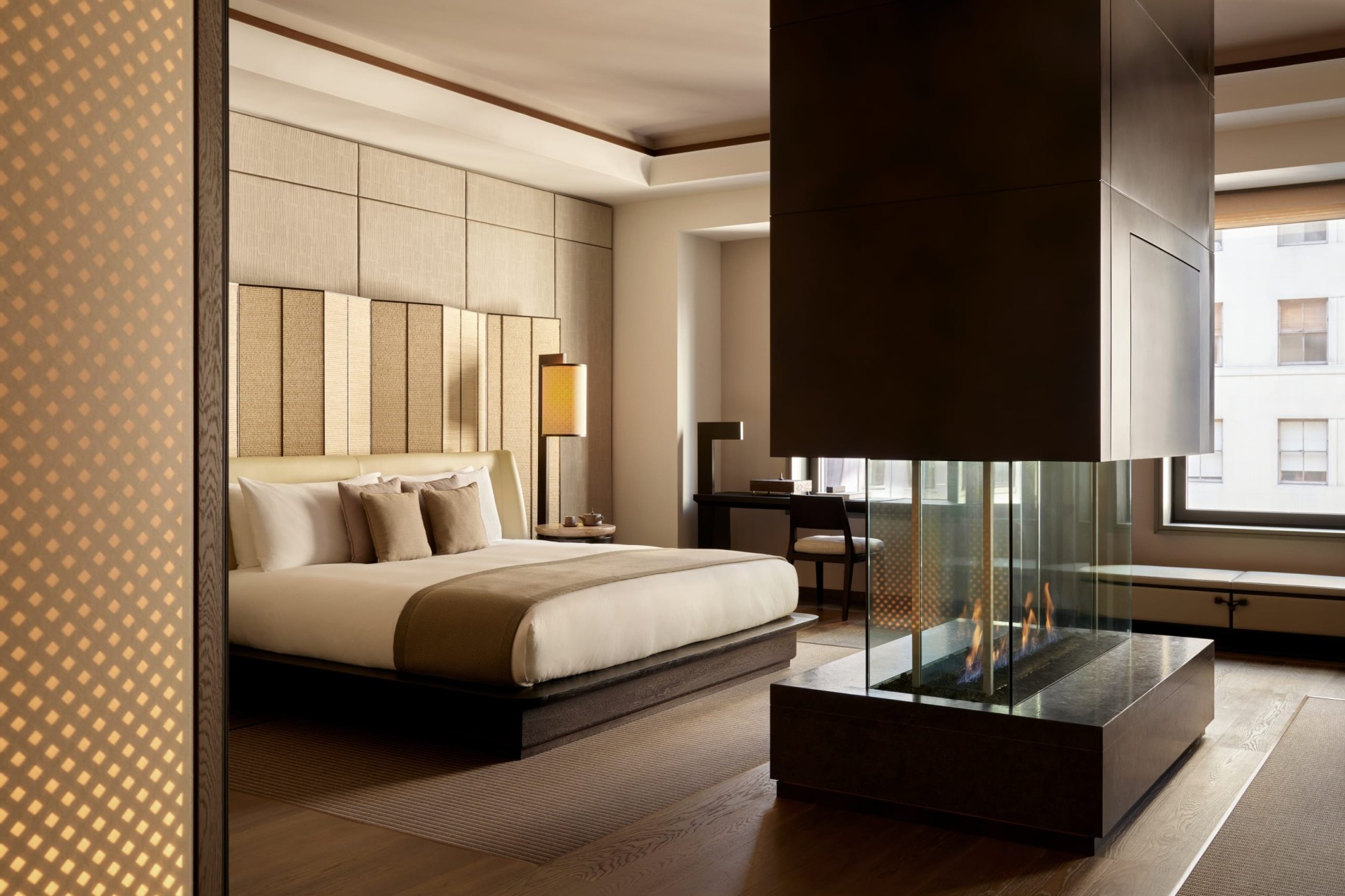 A stylish but minimalist-focused hotel room with a gas fireplace in the center