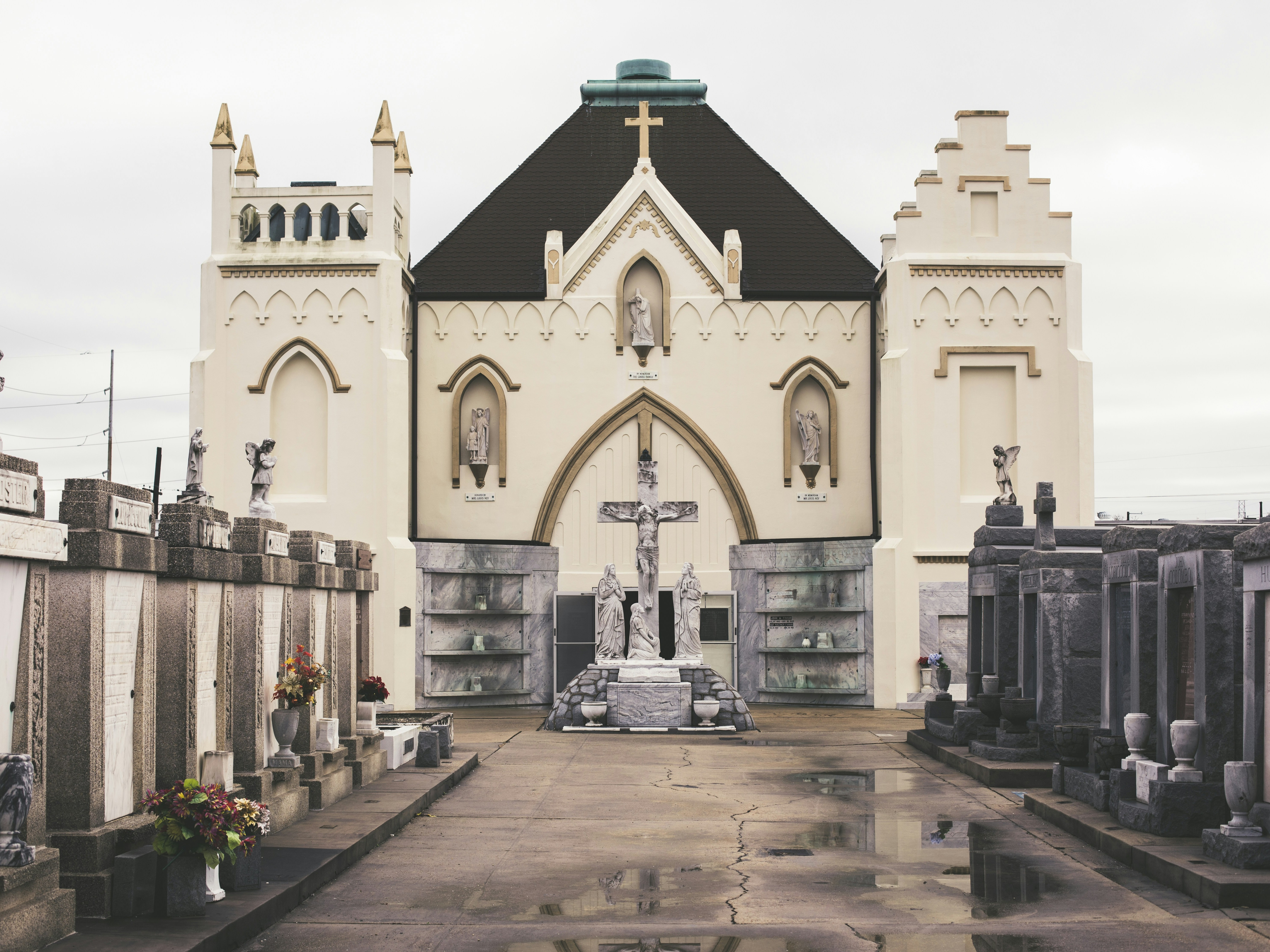 A symmetrical view of a cemetery with ornate tombstones and a church under an overcast sky.