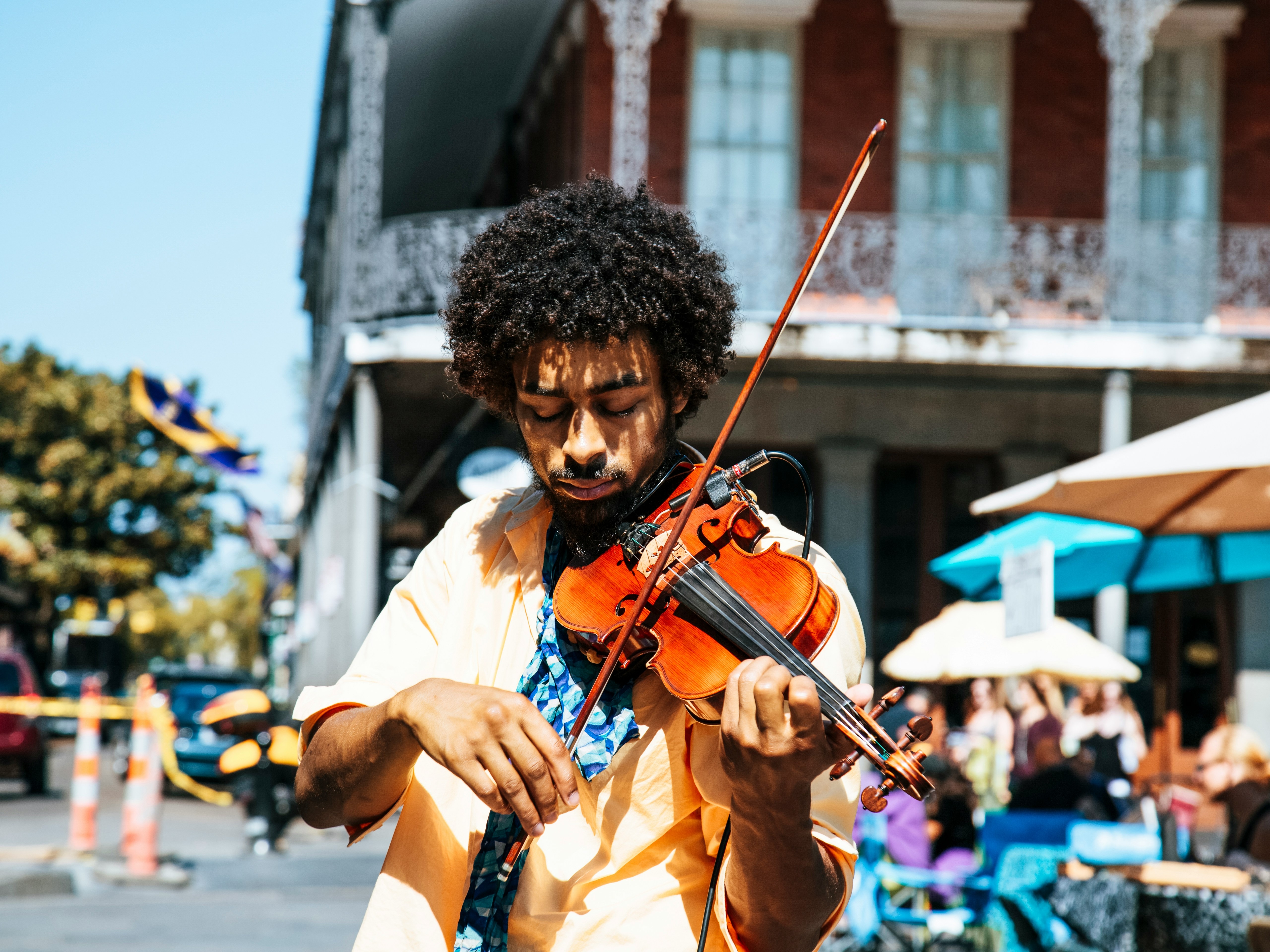 A person playing an acoustic violin and singing outdoors.