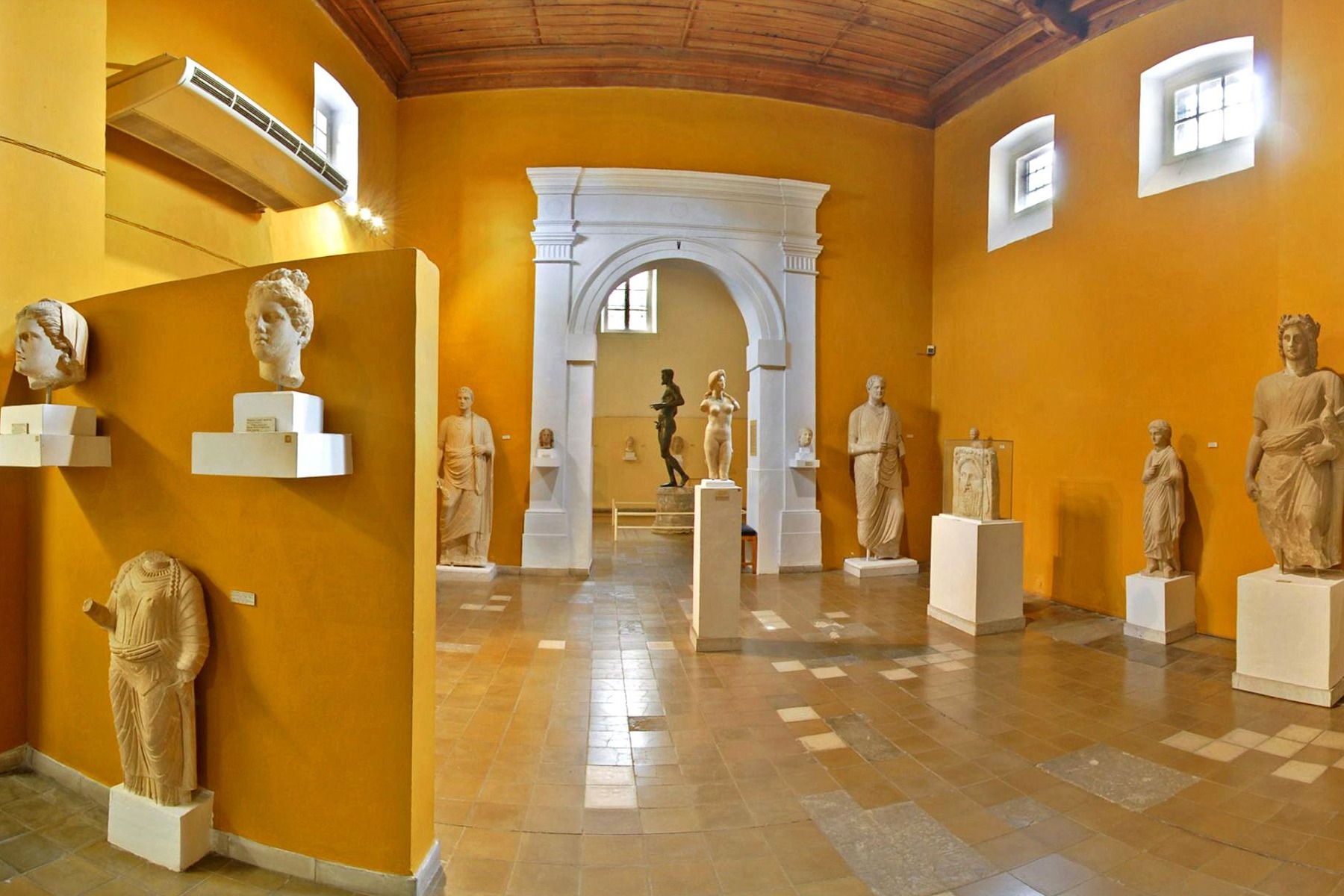 The Cyprus Museum in Nicosia houses the island's most significant collection of archaeological treasures, a large yellow room with a white molded arched door filled with ancient sculptures.