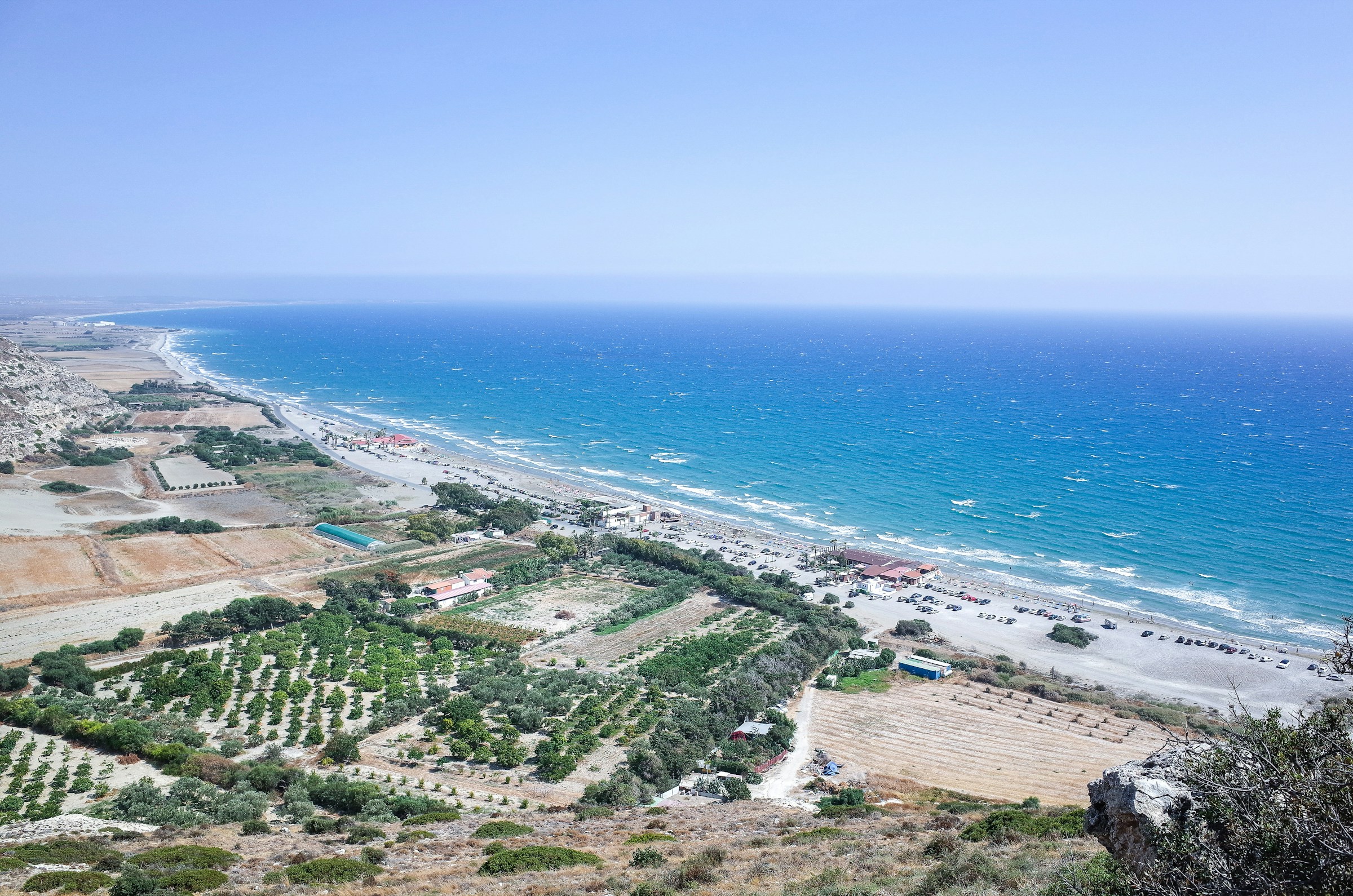 Aerial view of Kourion Archaeological Site, a white sand beach and a calm blue ocean during the day.
