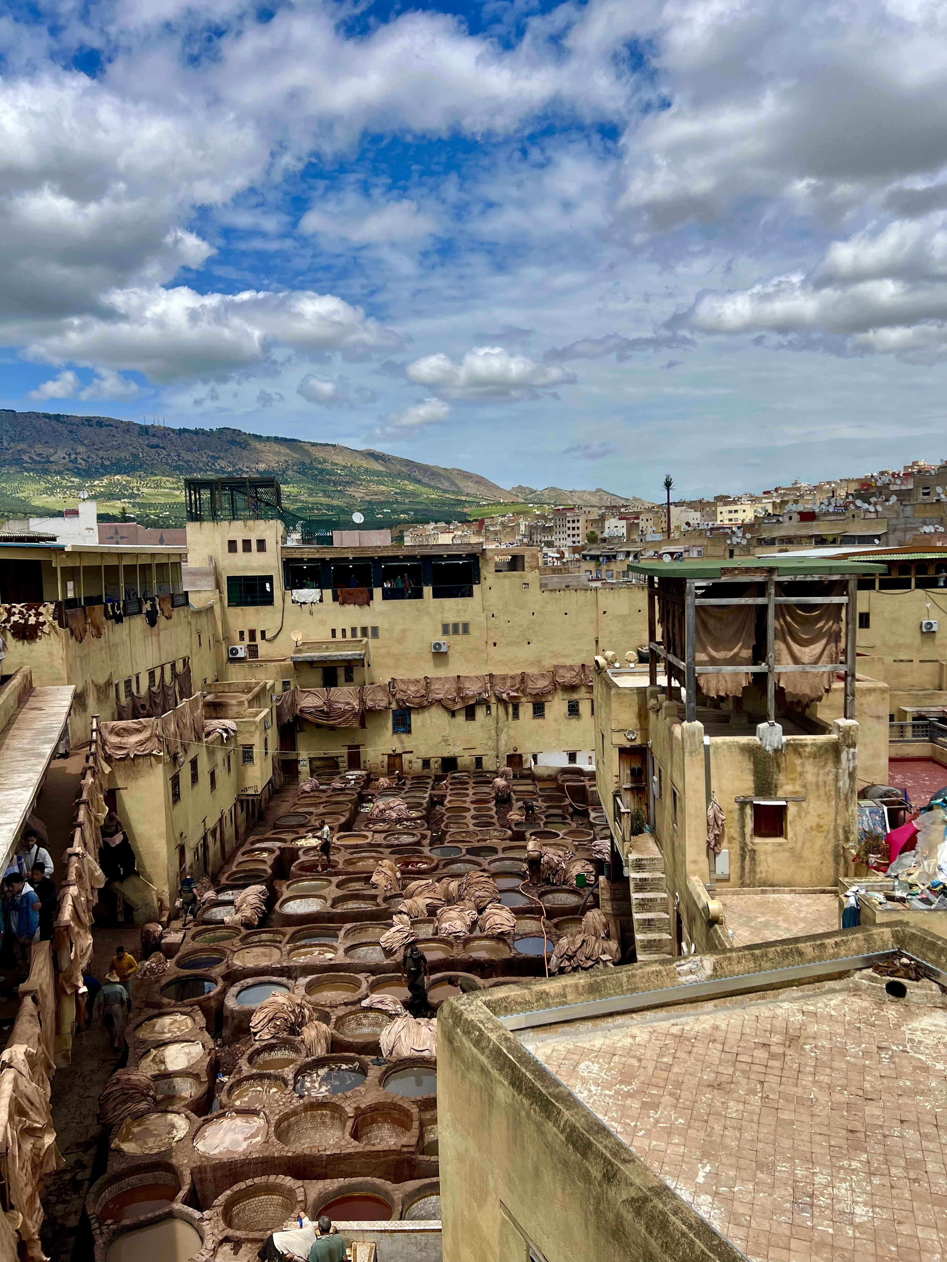 Rooftops of buildings on a sunny day dotted with clouds.