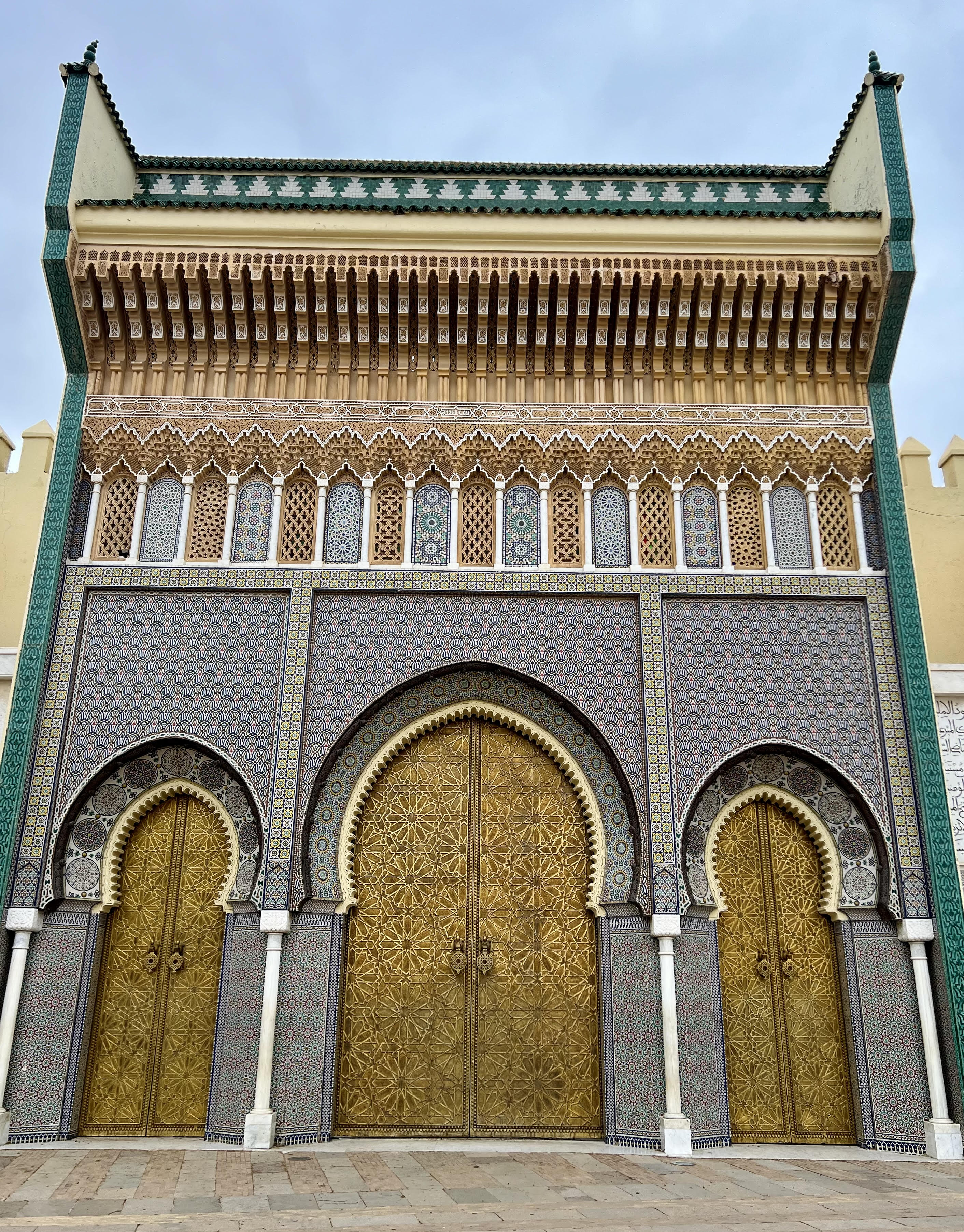 Golden doors line the front of a bright, tiled building on a sunny day.