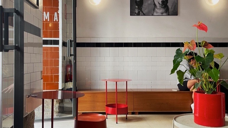 Interior of a hip cafe with subway tile walls and red stools.