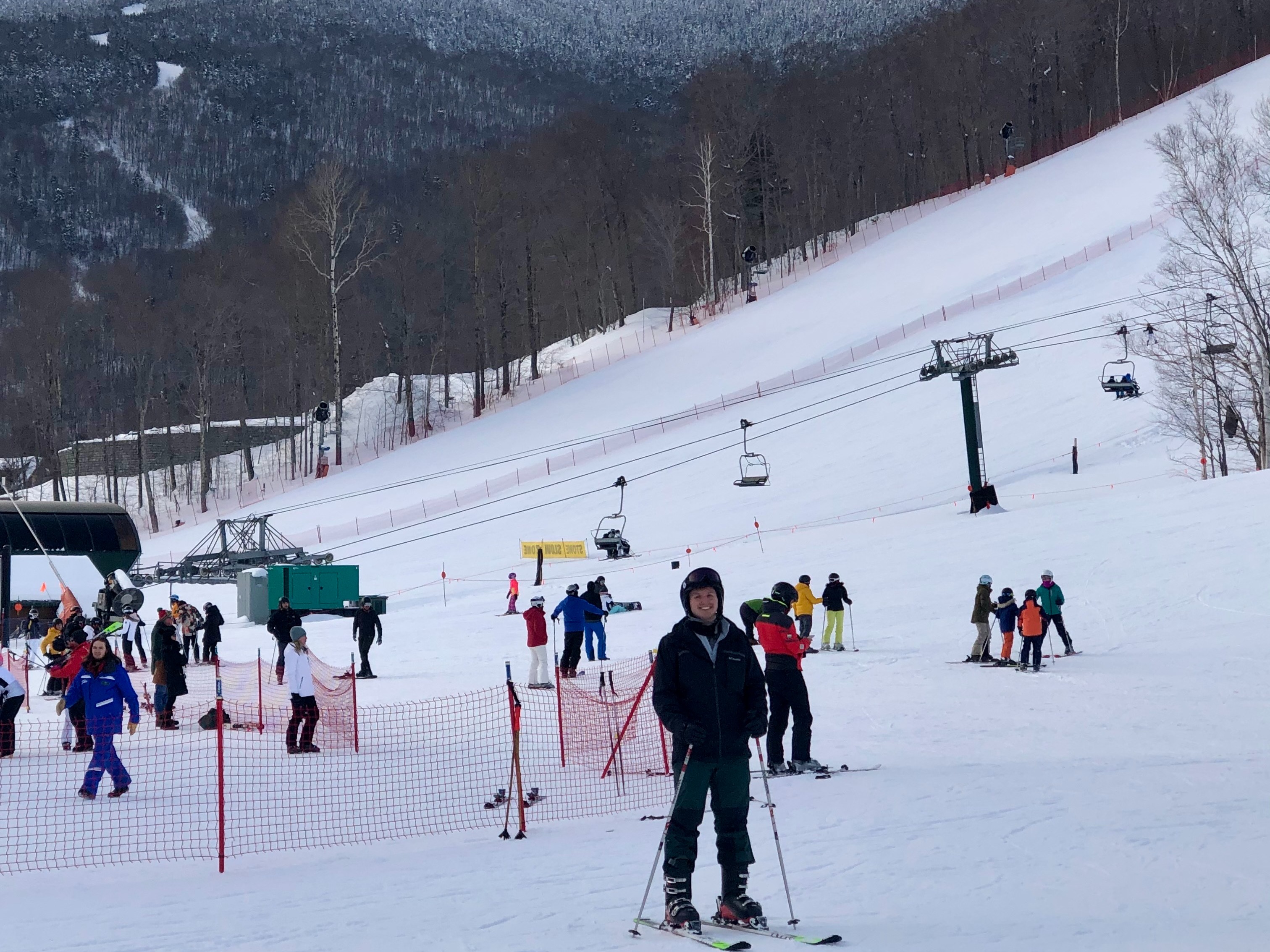 A skier poised for descent on a lively, snow-clad mountain slope with a scenic backdrop.