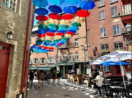 A vibrant street adorned with a canopy of colorful umbrellas, creating a whimsical and picturesque urban scene.