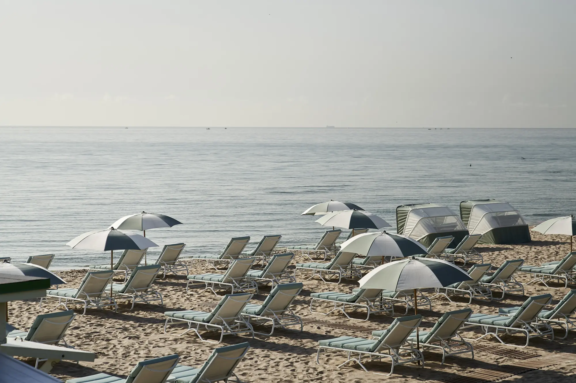 Rows of Four Seasons' beach loungers, some with umbrellas, fill a quite stretch of beach in front of the resort