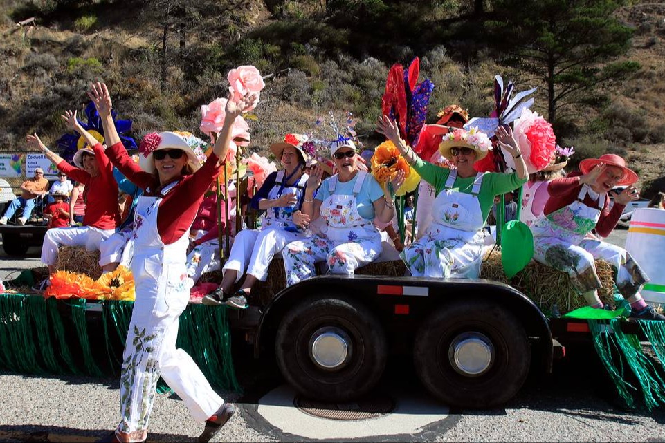 People wearing white overalls sitting on a parade float outside during the daytime