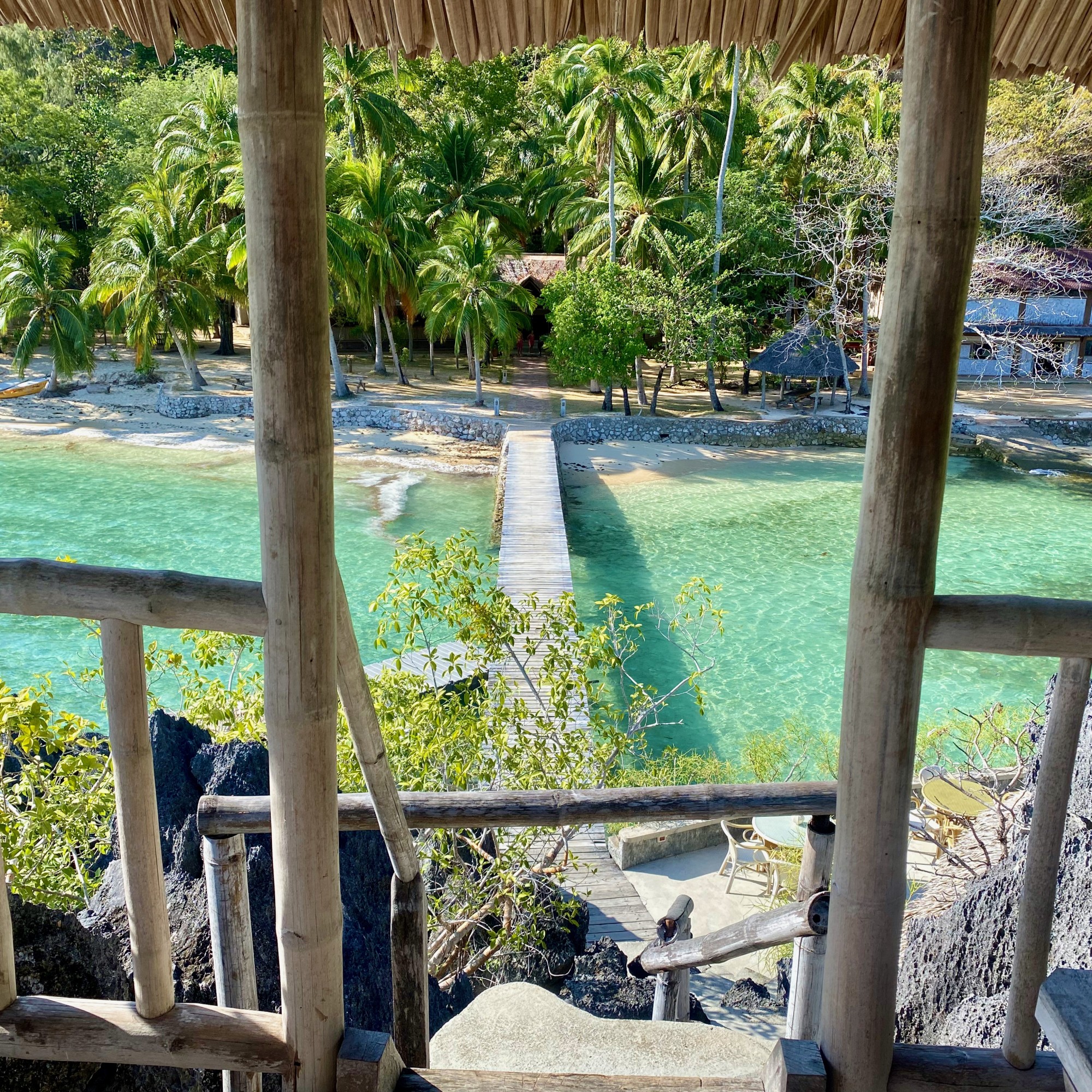 An overwater building with a boardwalk over the water to the beach.