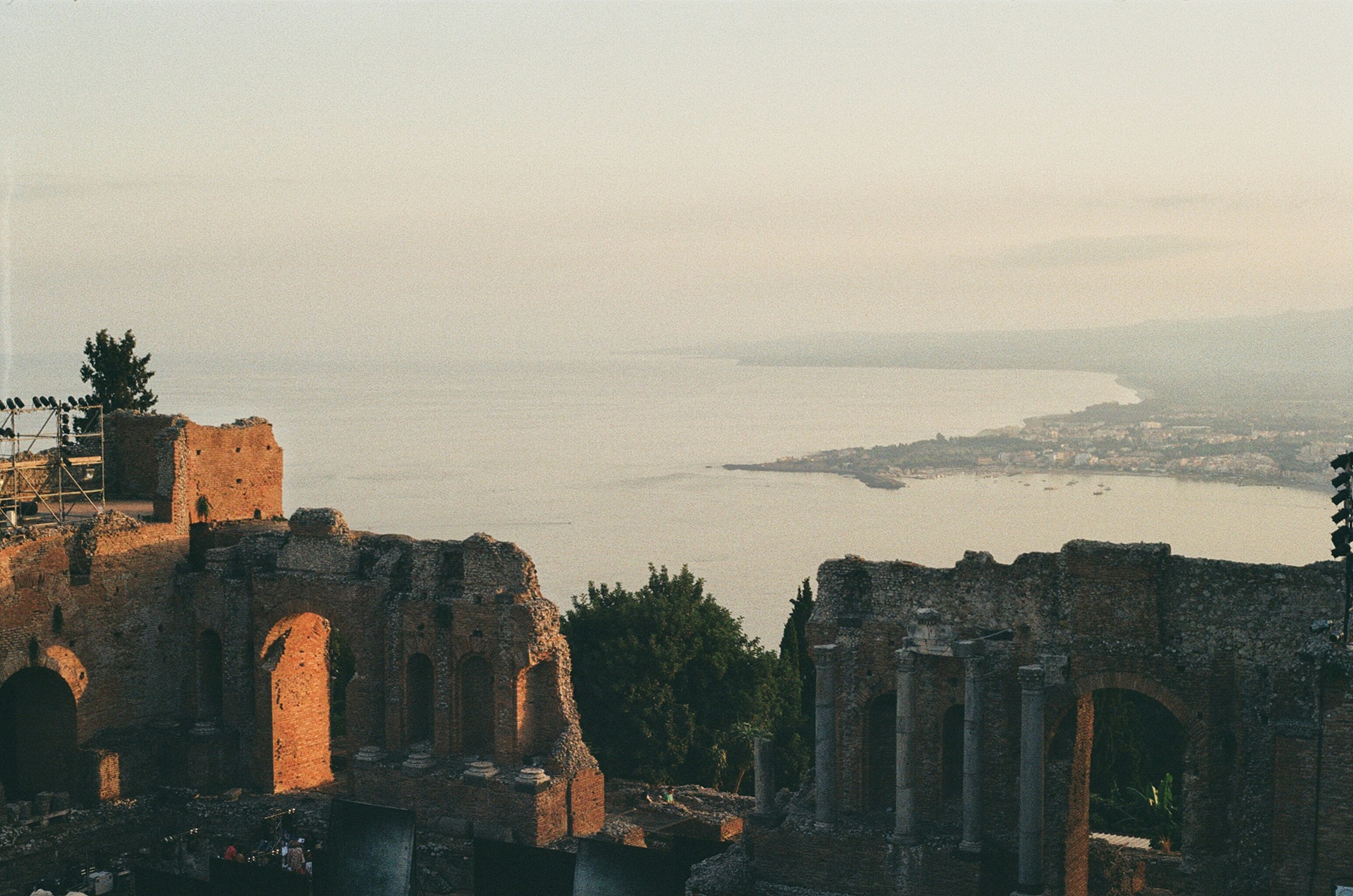 Hilltop view of Taormina with a body of water in the background.