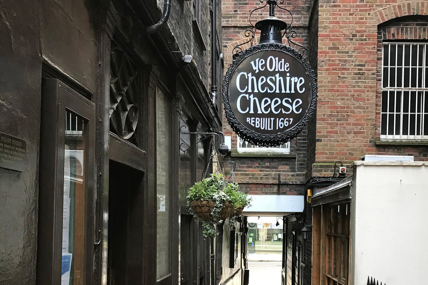 A narrow alley with a hanging sign that reads "Ye Olde Cheshire Cheese."