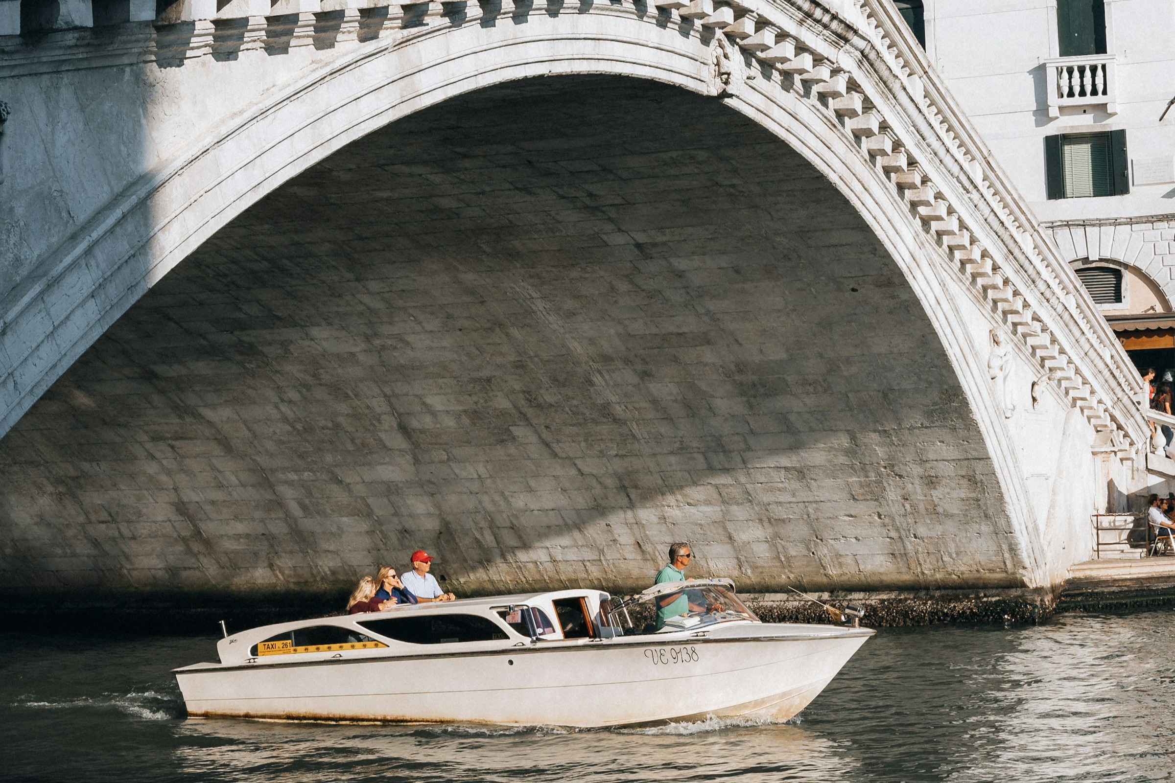 A boat traveling under a bridge at Venice.