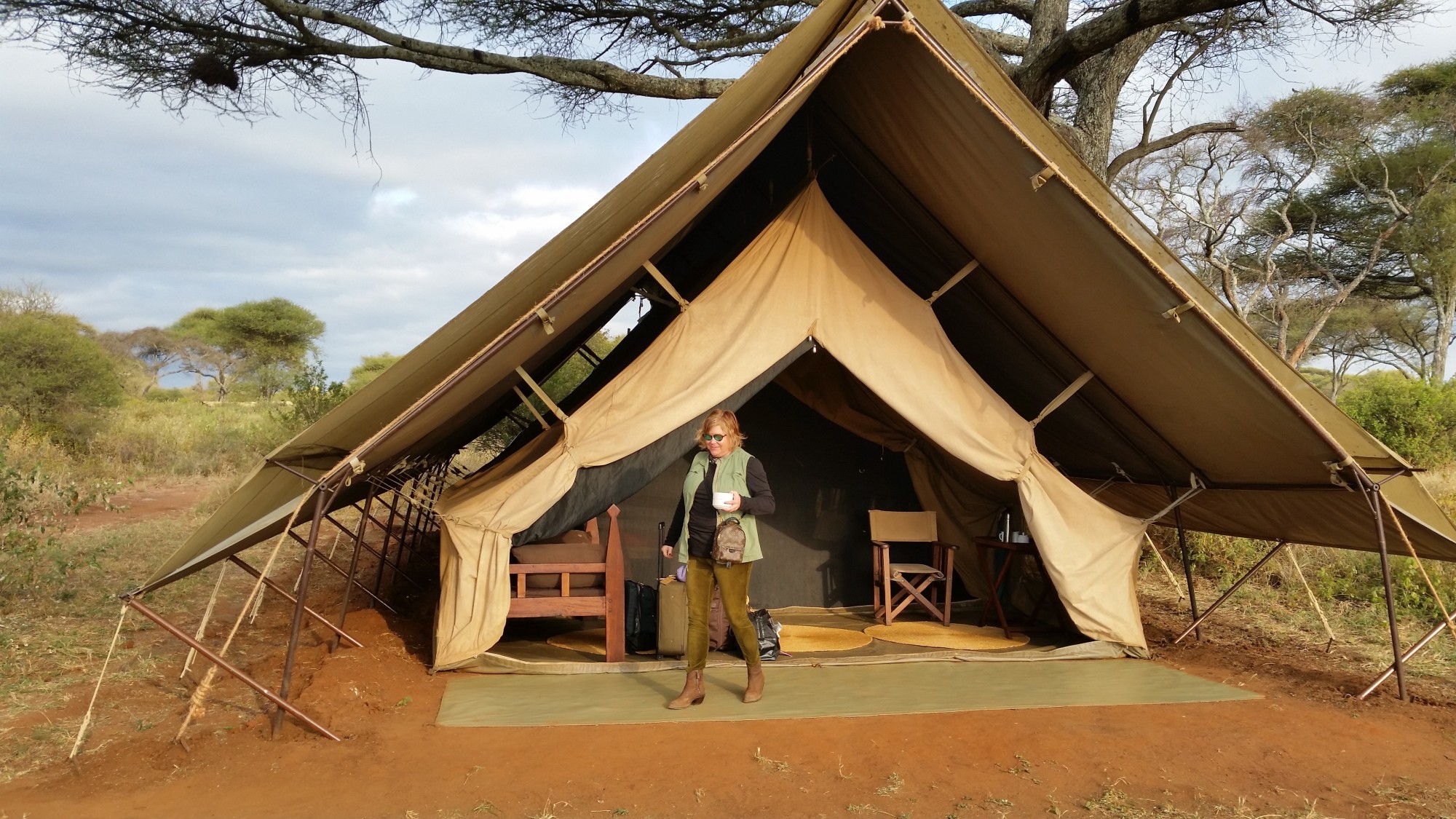 Advisor standing in front of a large canvas tent set up in the desert on a partly cloudy day.
