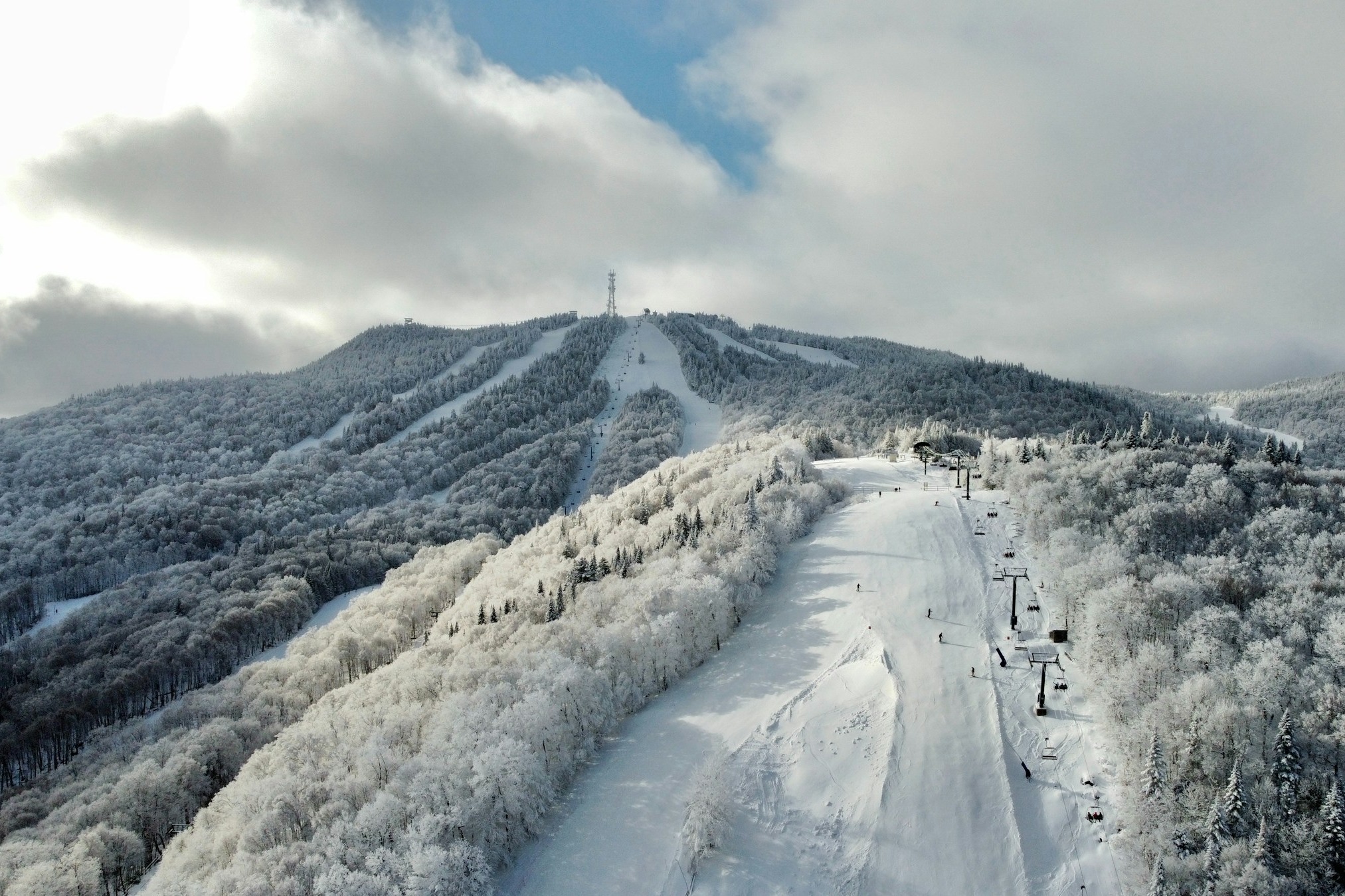 A snow covered mountain with a ski lift on top of it.