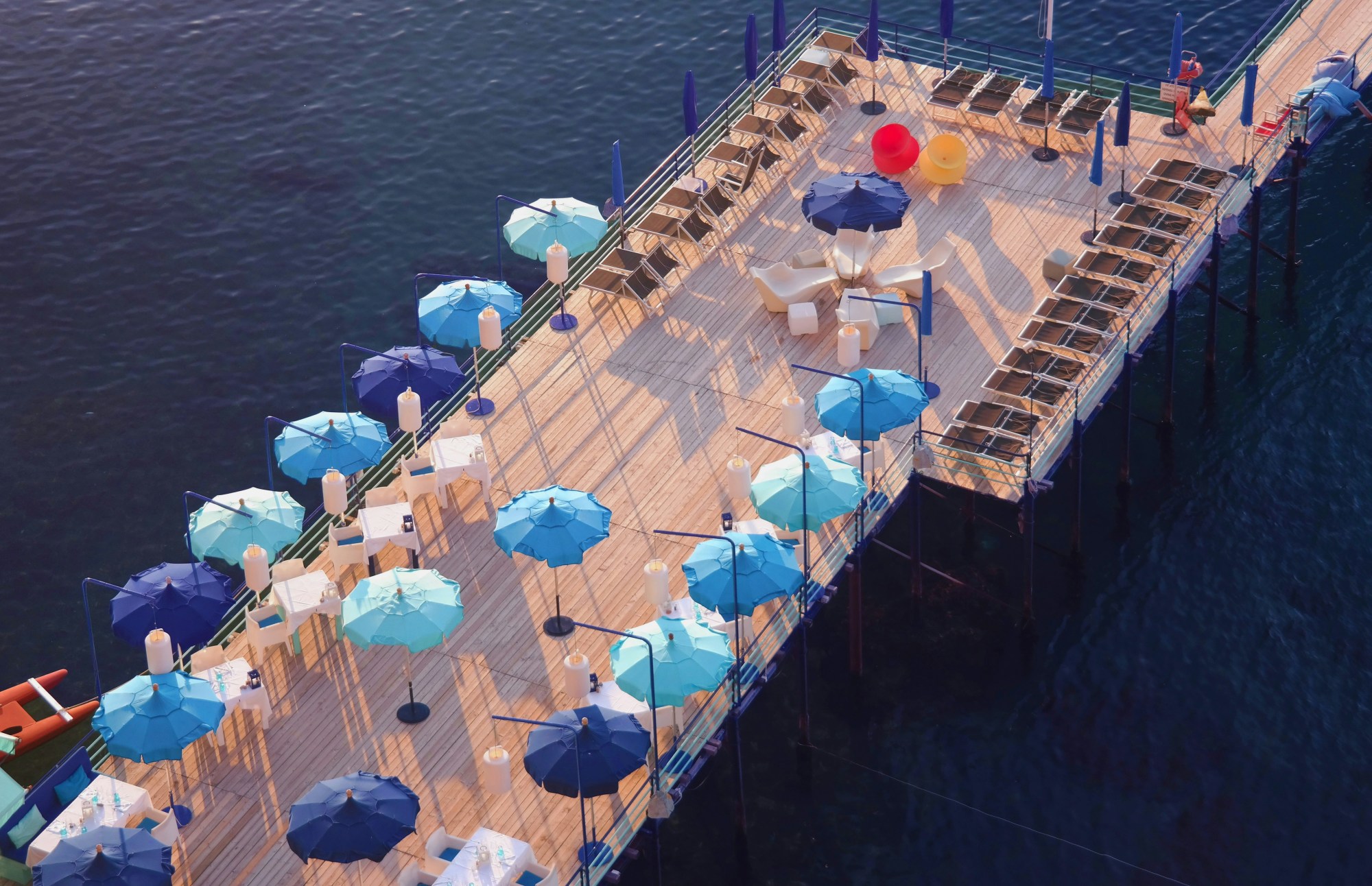 Blue canopy umbrellas on a wooden deck above a body of water