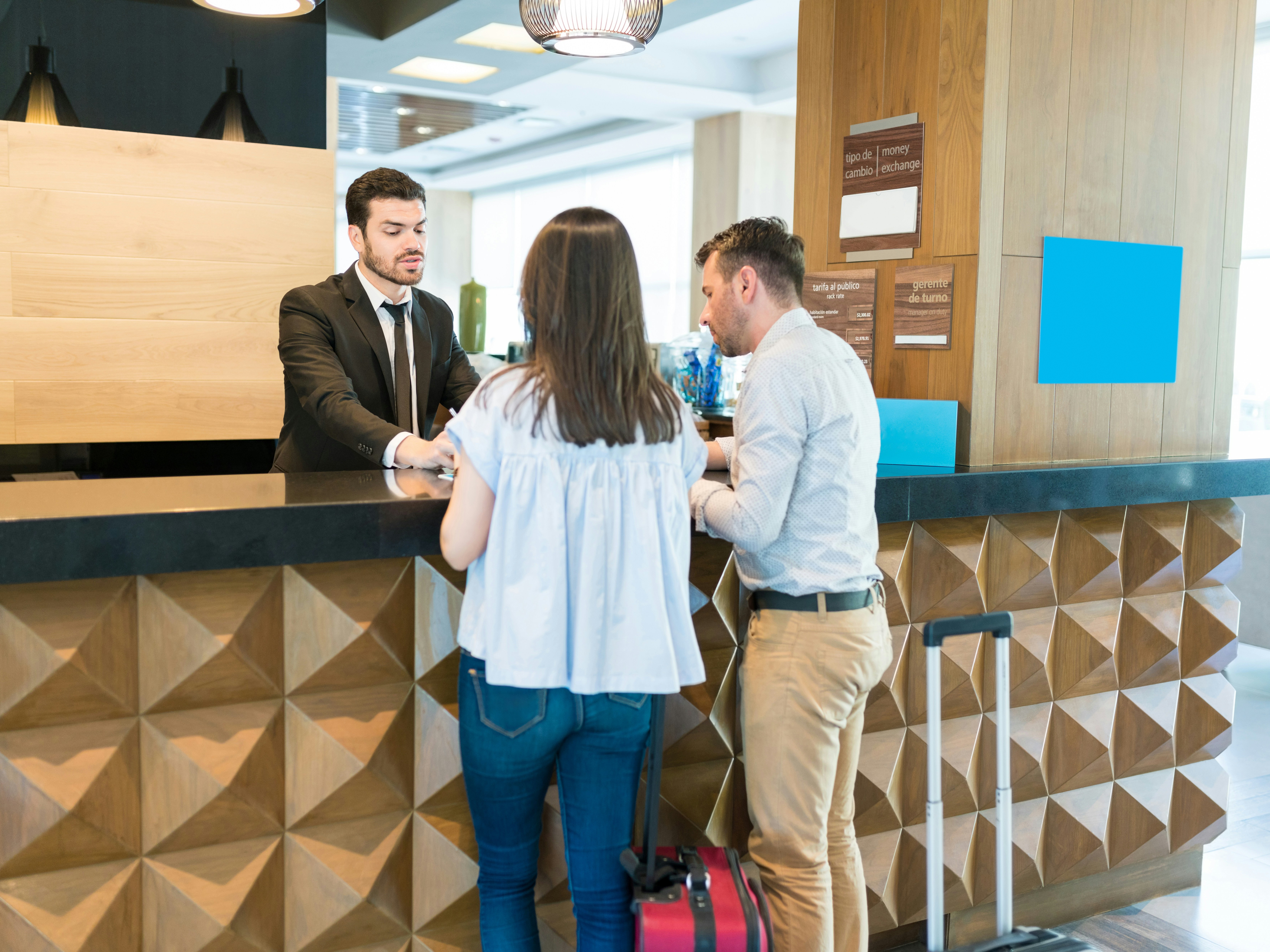 Two individuals at a hotel reception desk interacting with a staff member.
