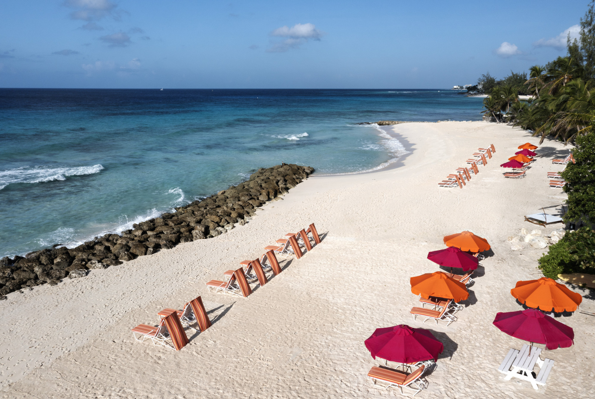 a Caribbean beach dotted with pink and orange umbrellas