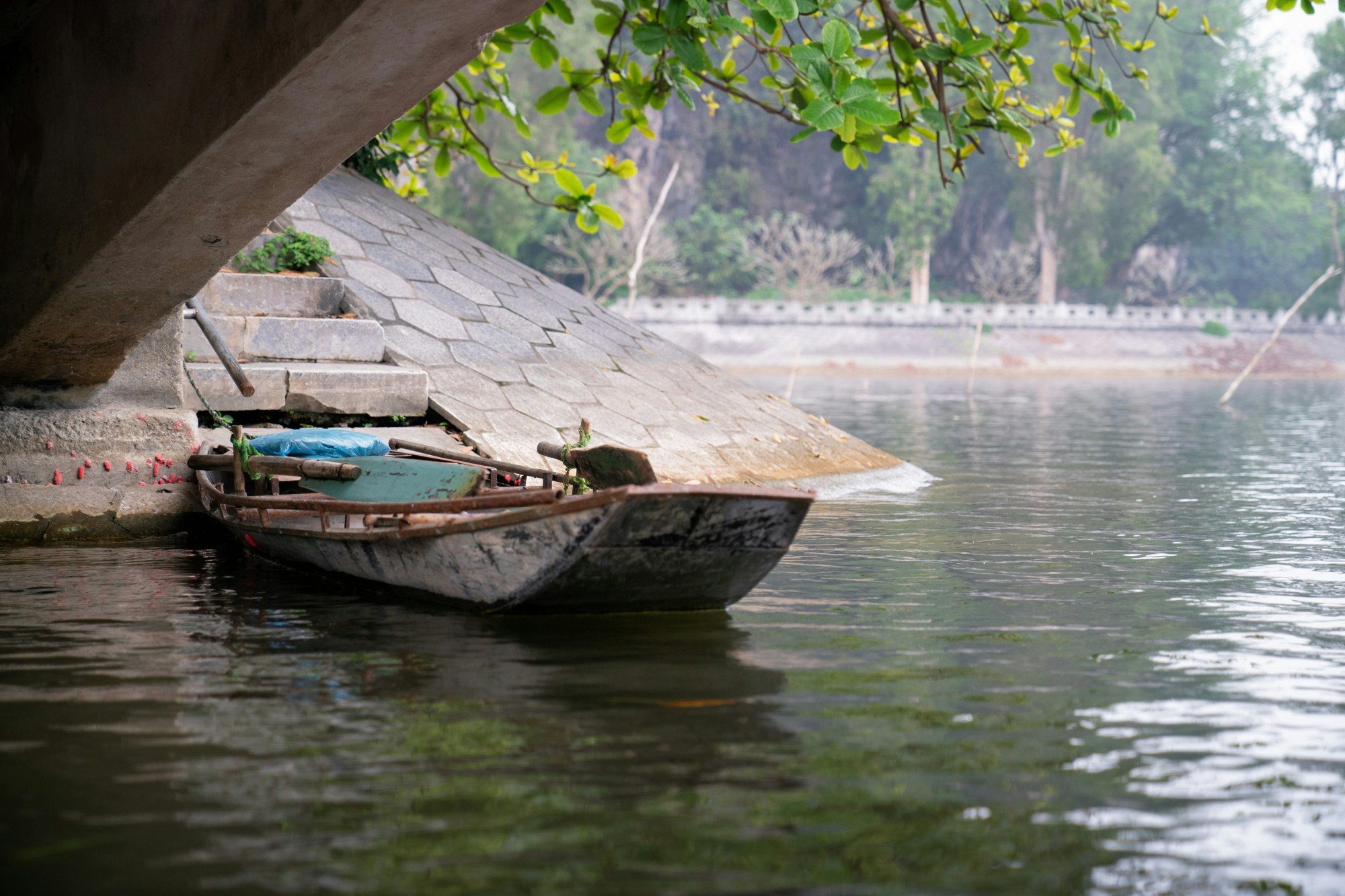 A wooden boat in the water under a bridge