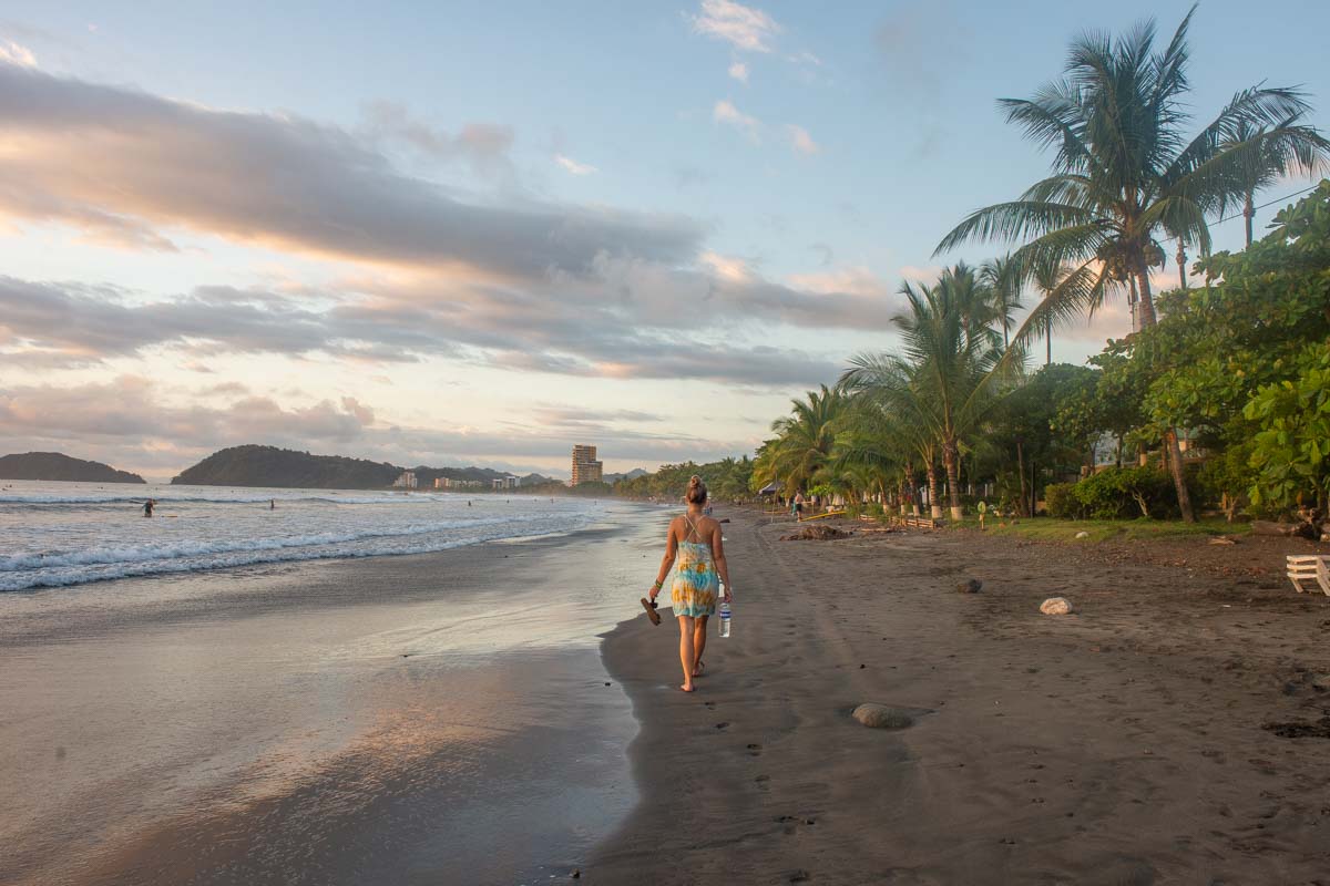 A person walking along a beach shore during a sunset