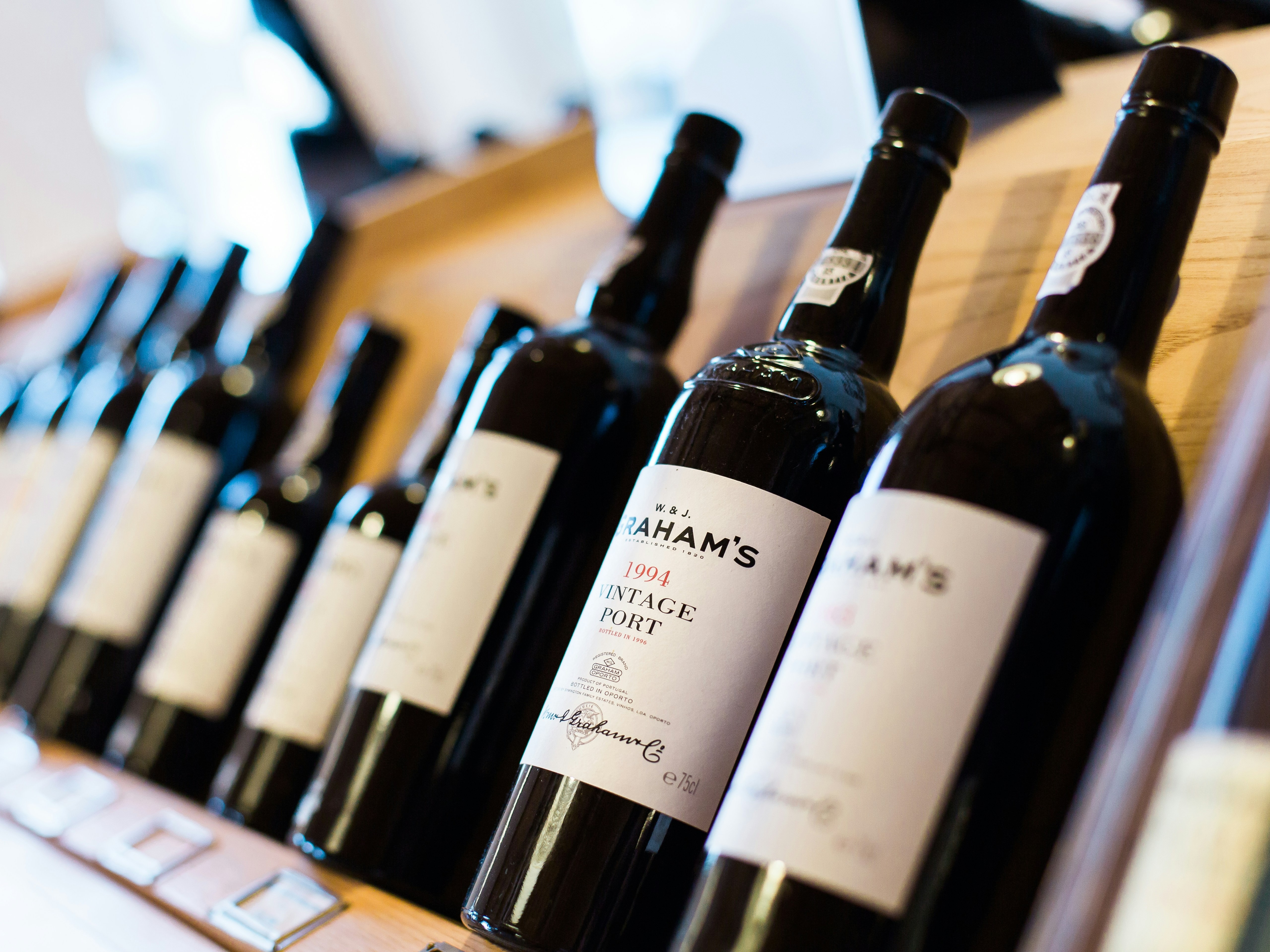 The image shows a row of wine bottles on a wooden shelf.