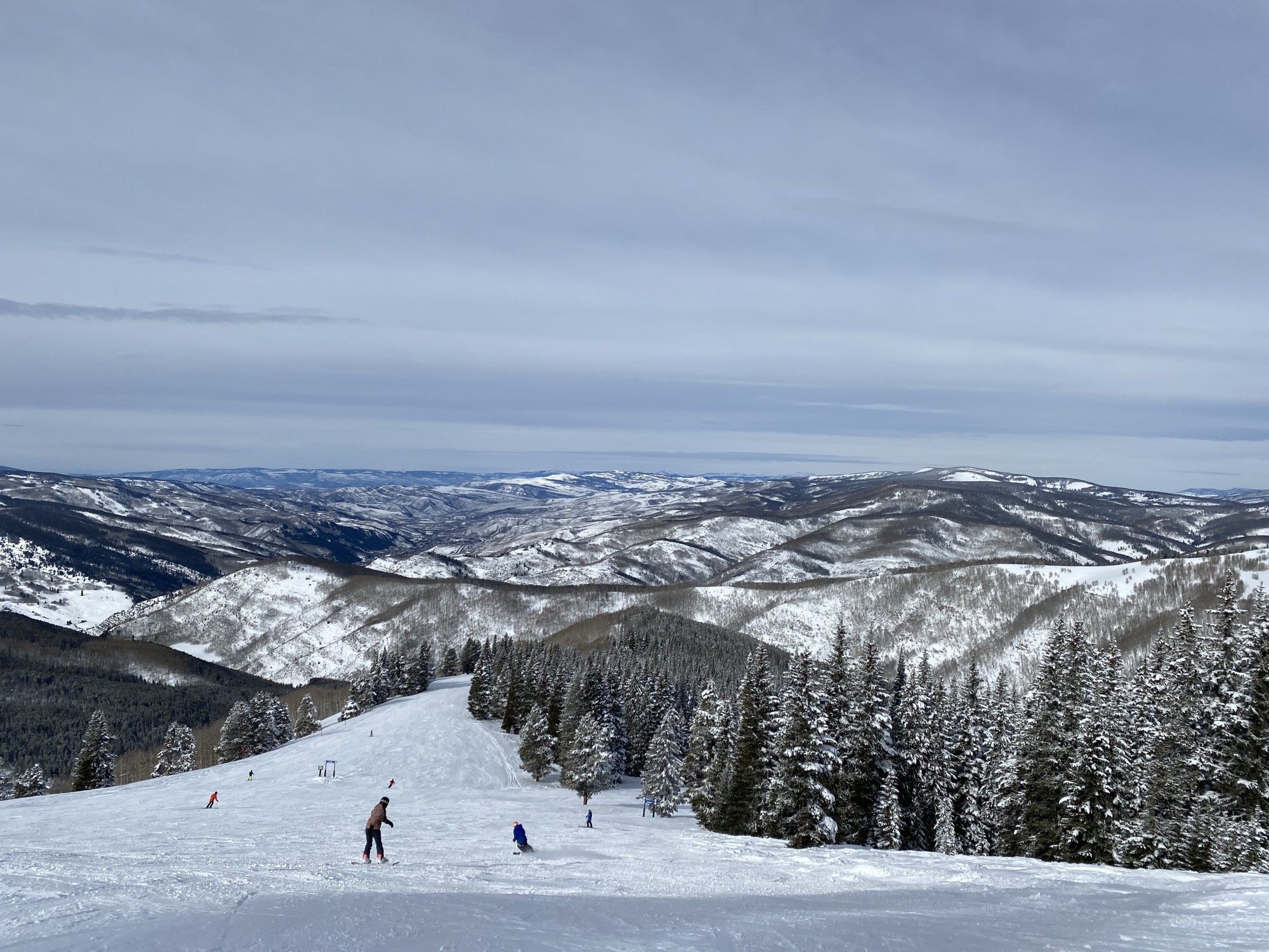 People skiing down a snow-covered mountain during the daytime