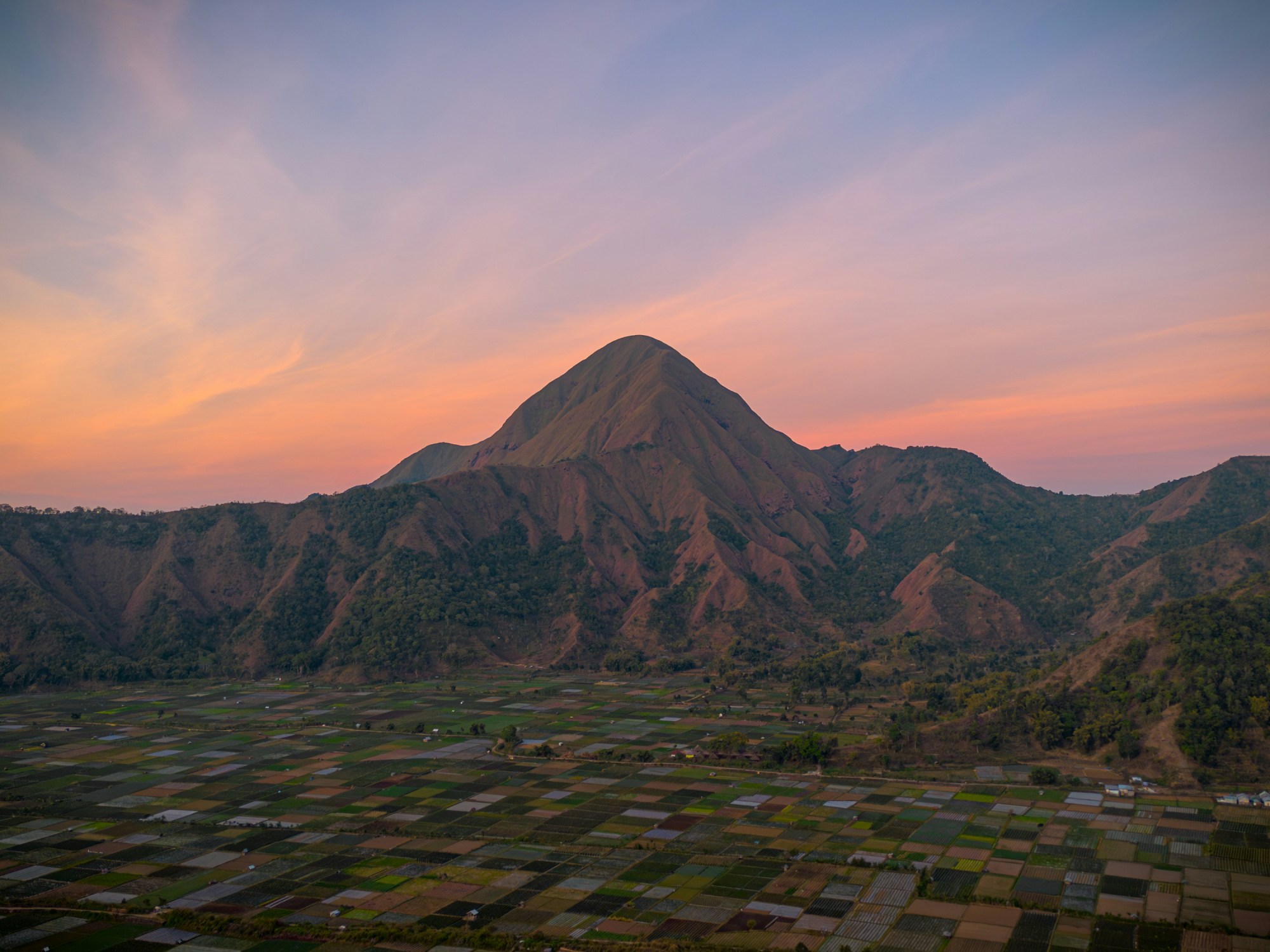 View of a mountain during a sunset making the sky purple and orange