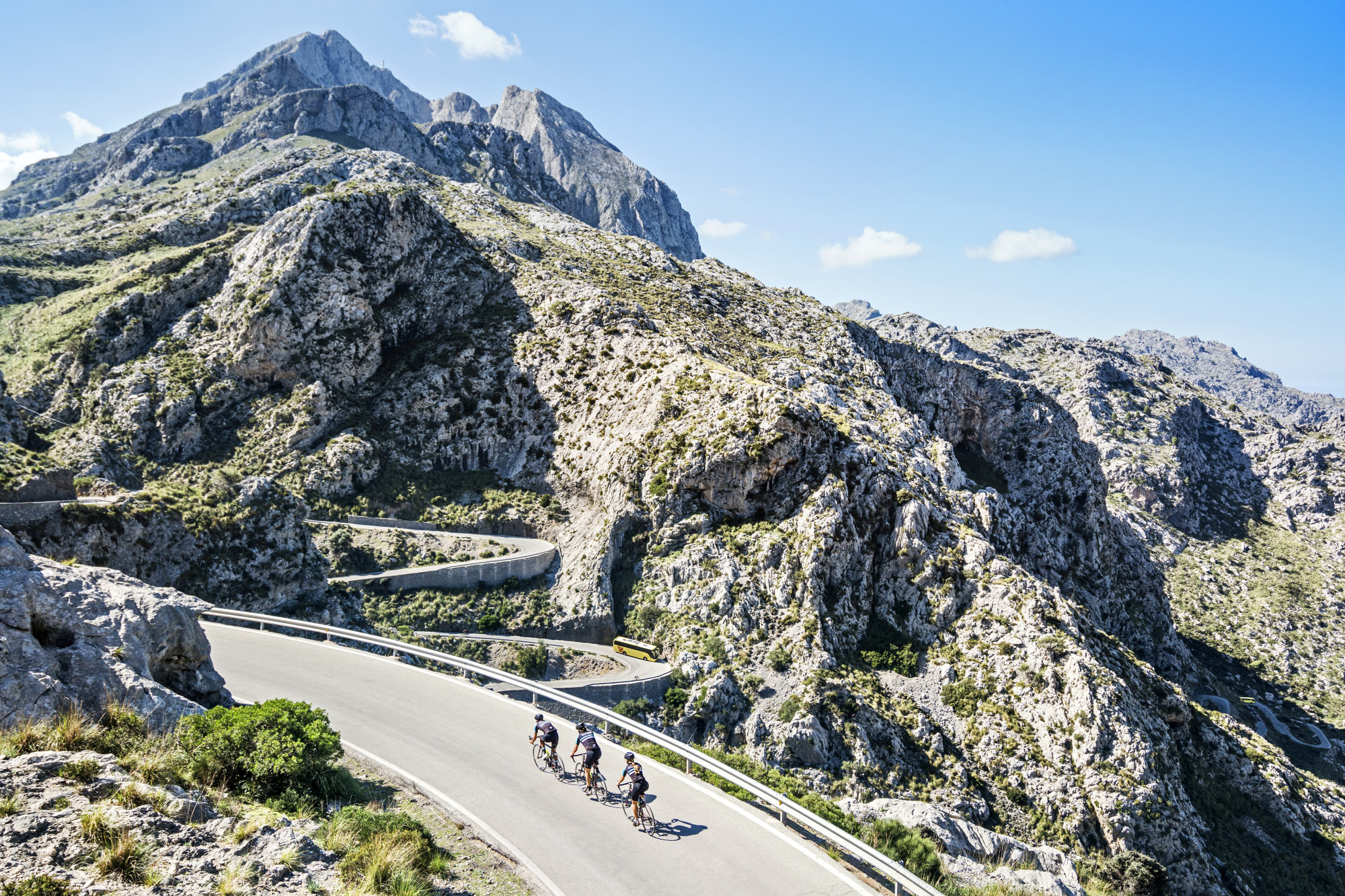 a group of bikers head up a road amid a rocky mountain