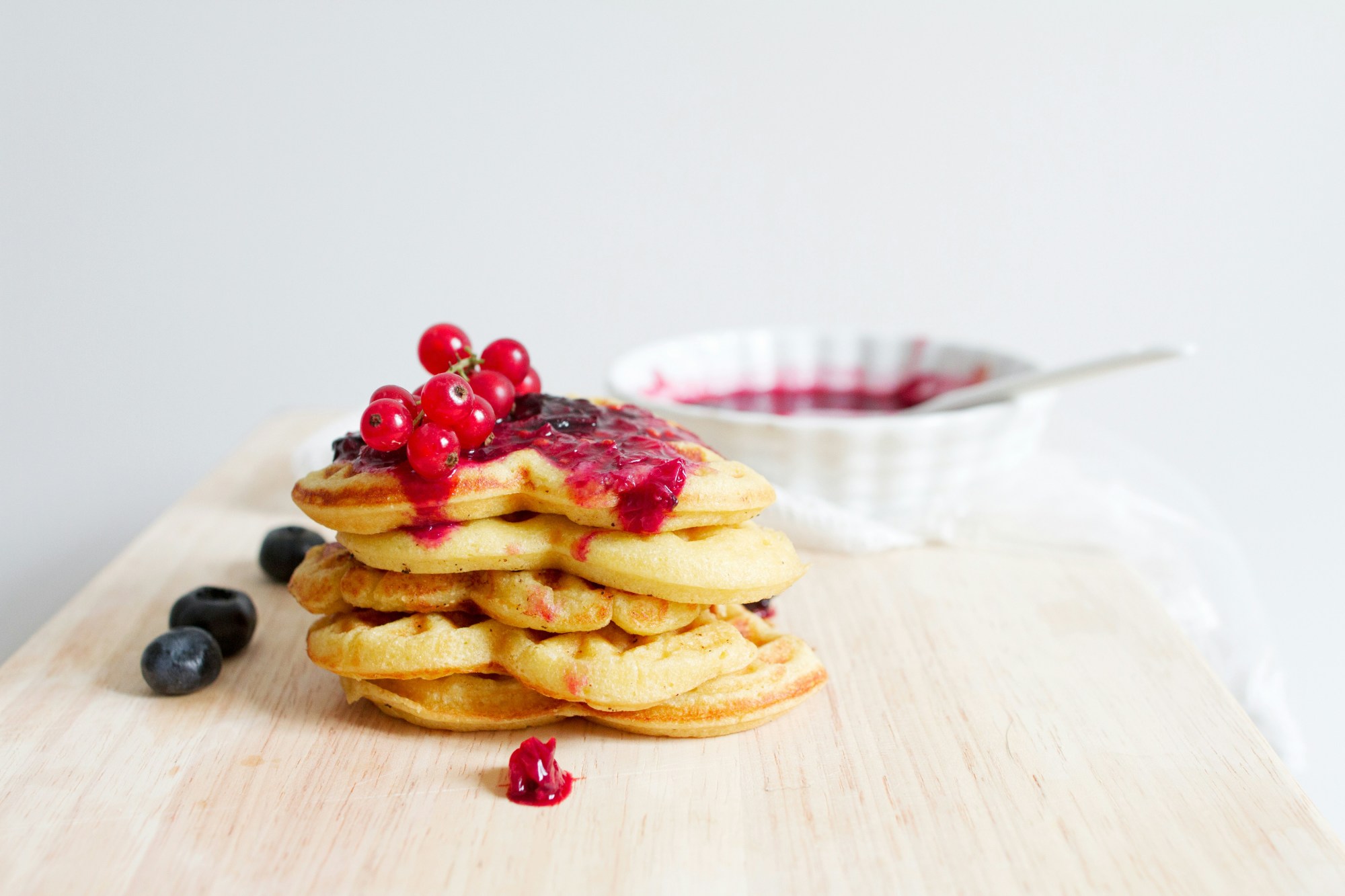 Pancakes with red and blue berries on a plate.