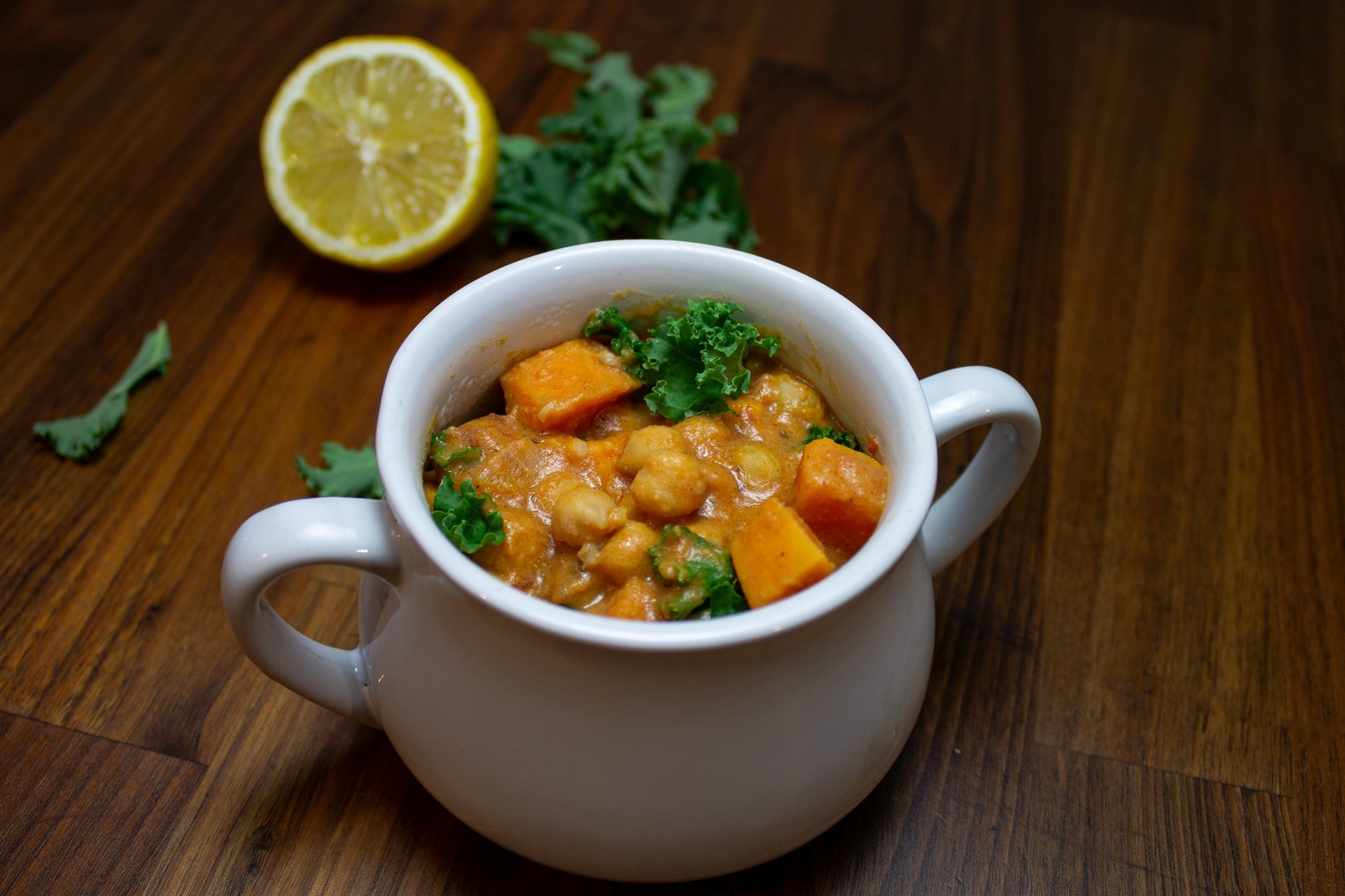 A bowl of curried chickpeas with parsley and lemon garnish.