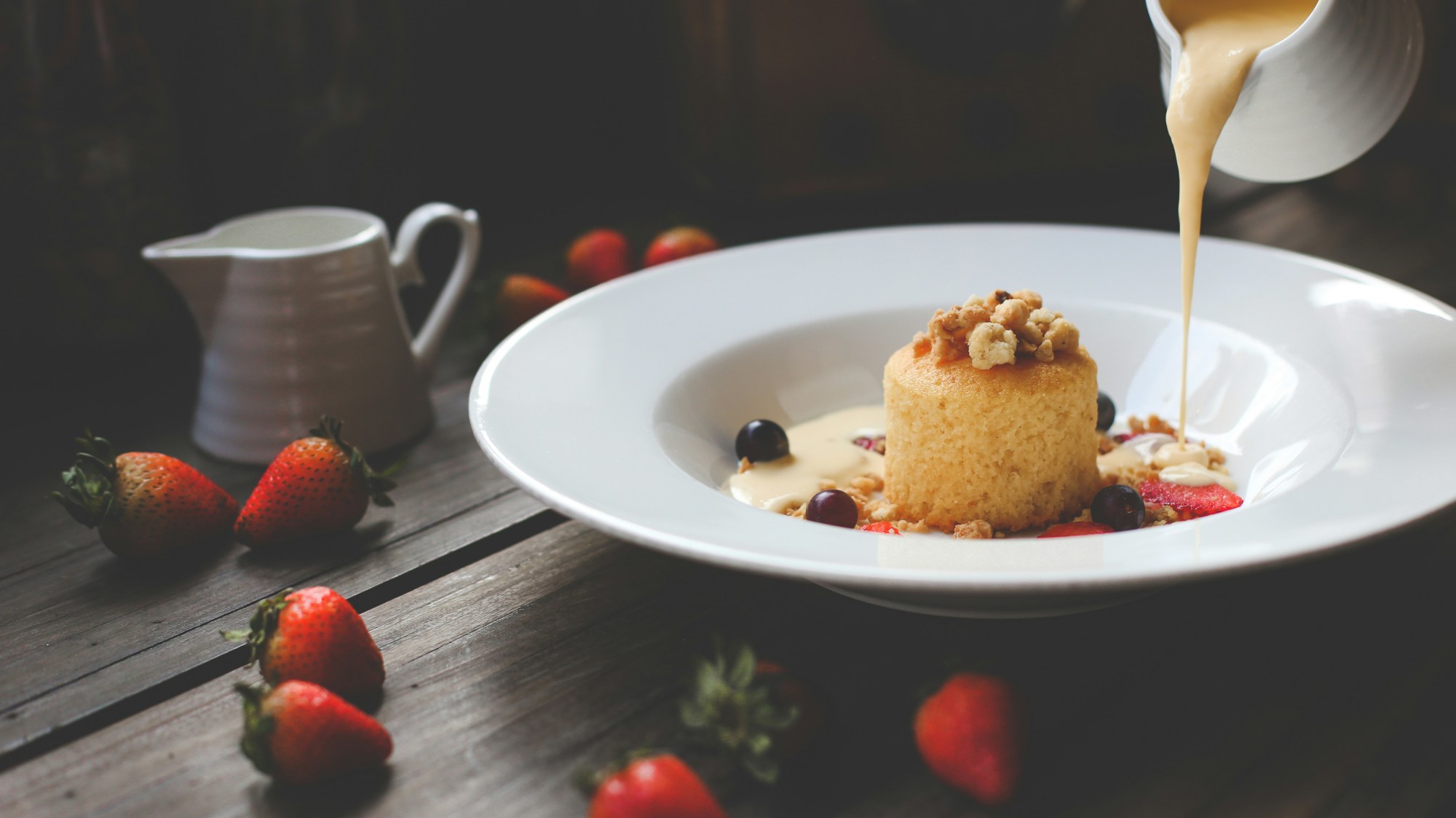 Dessert on a white plate with sauce being poured on it.