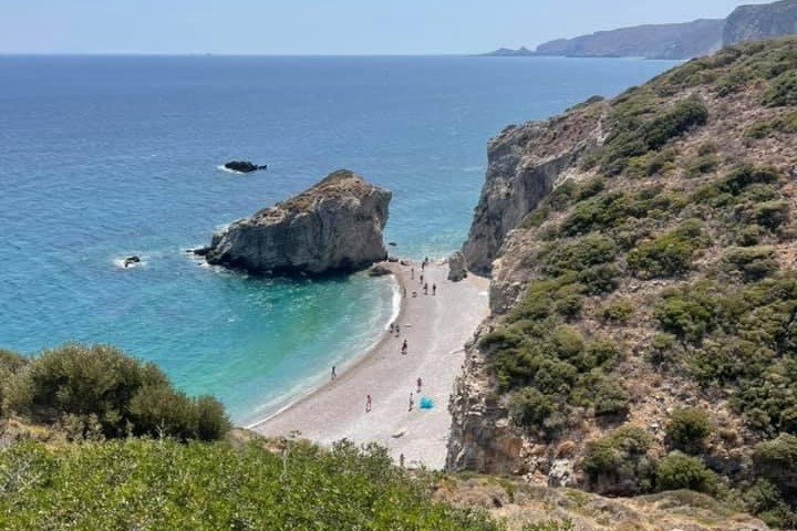 A beach coastline next to rocky cliffs during the daytime