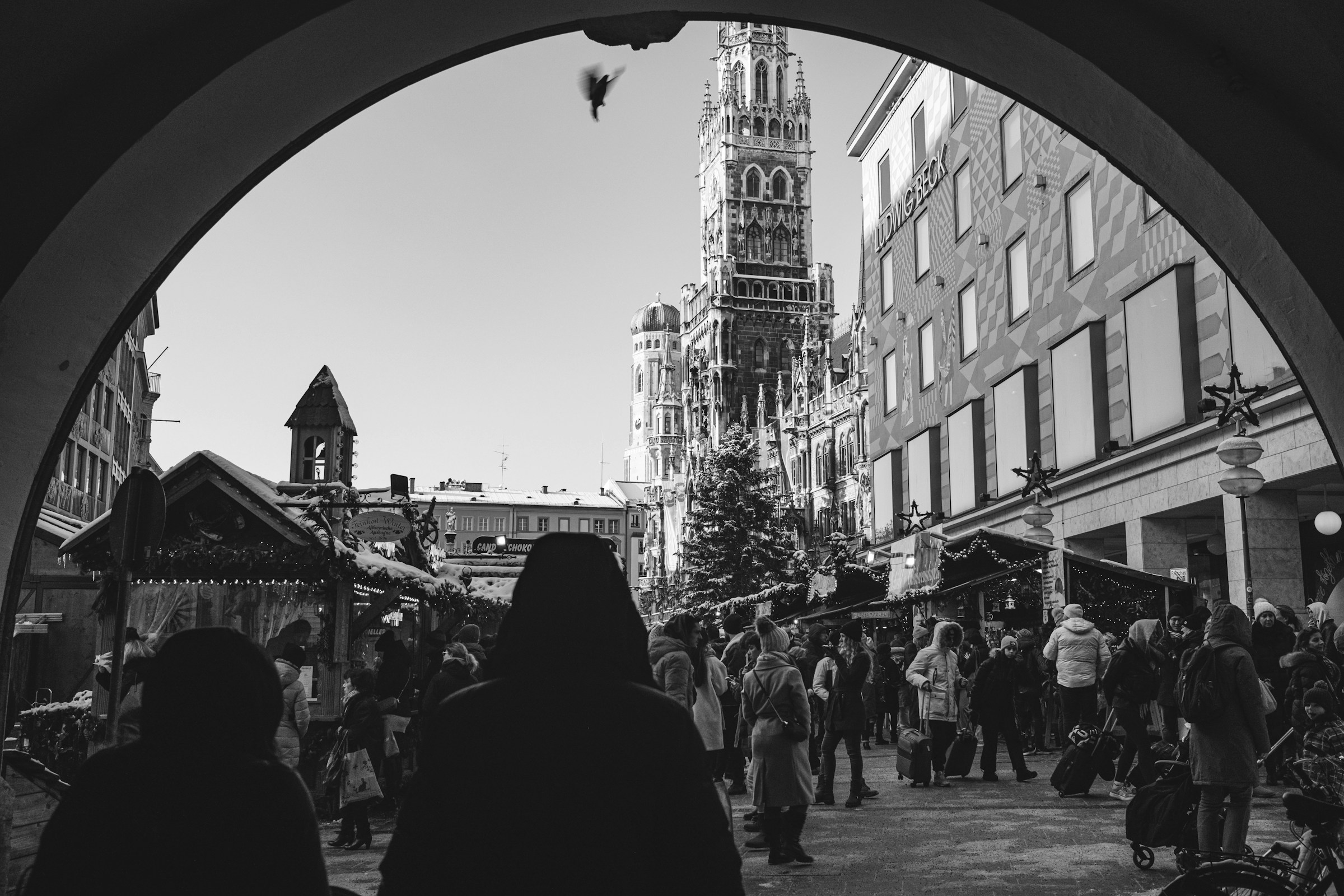 A black and white photo of people walking around and outside market