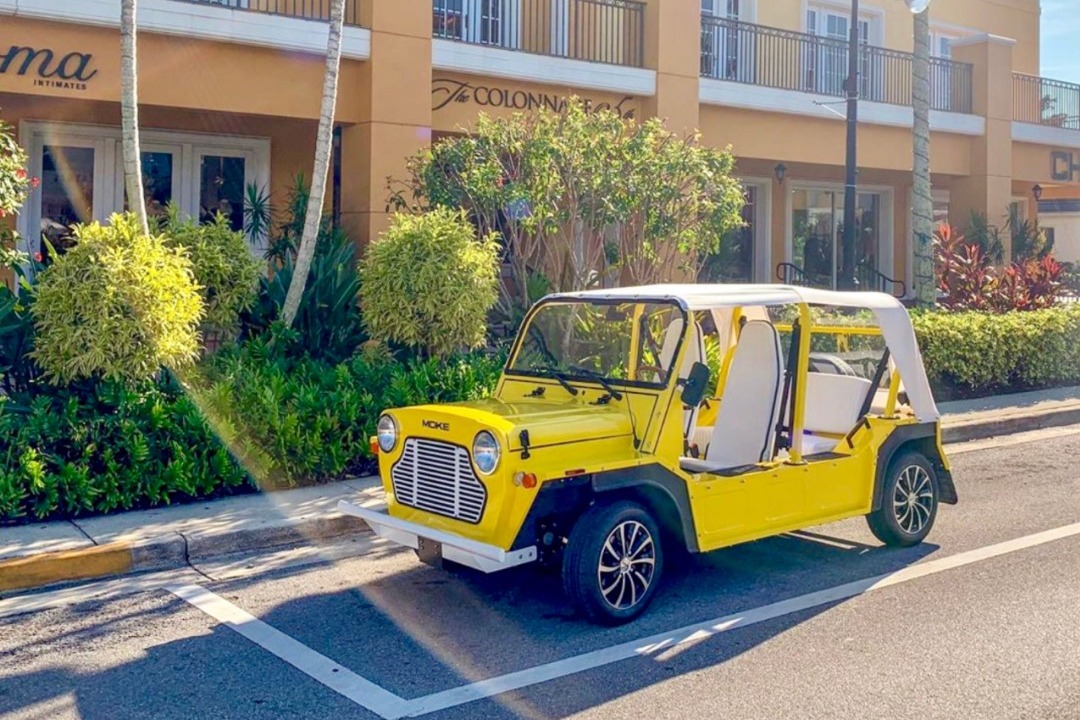 A yellow car without doors parked in front of an orange-painted building