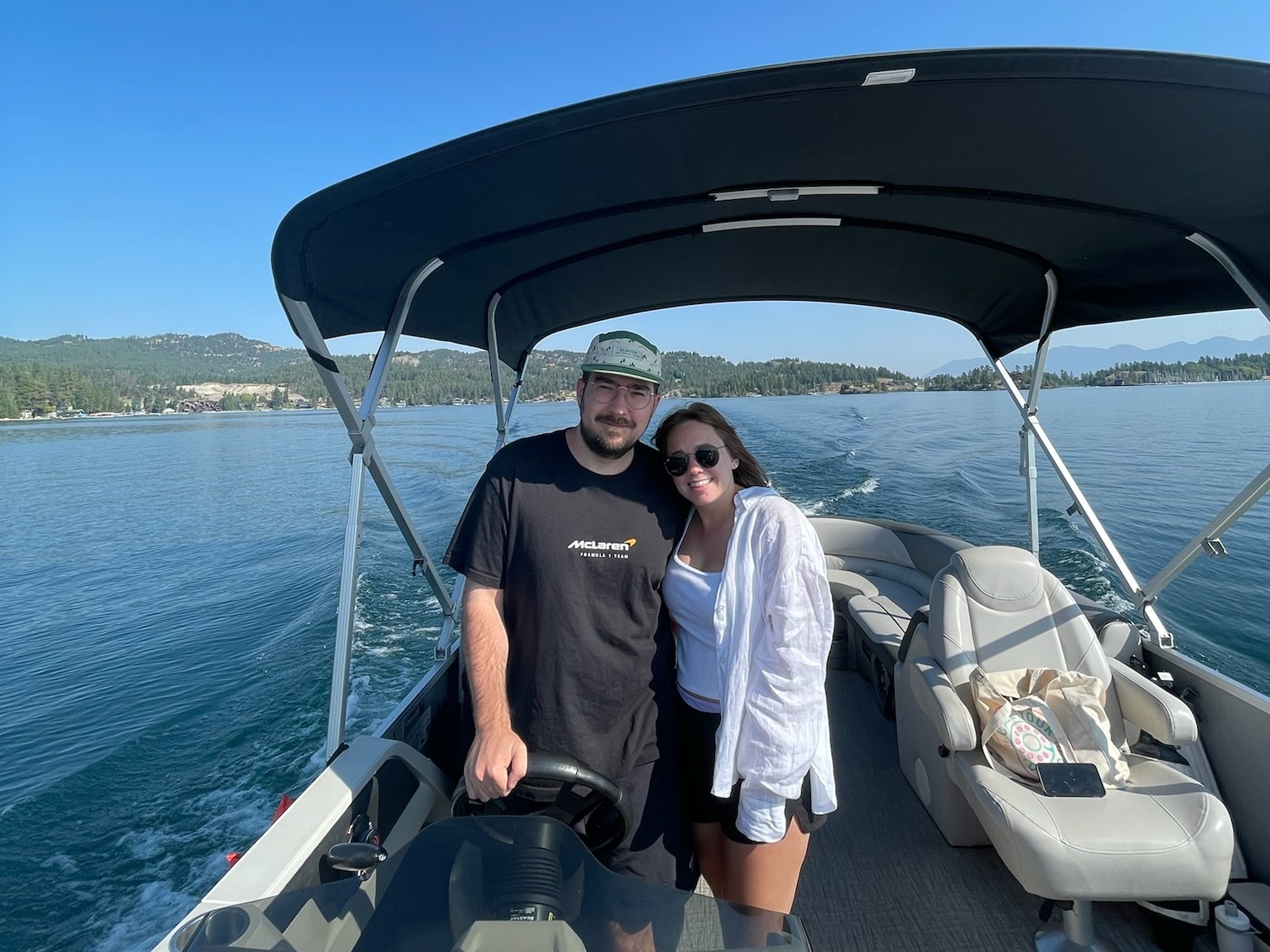 Two people posing for a photograph together on a boat sailing down a lake