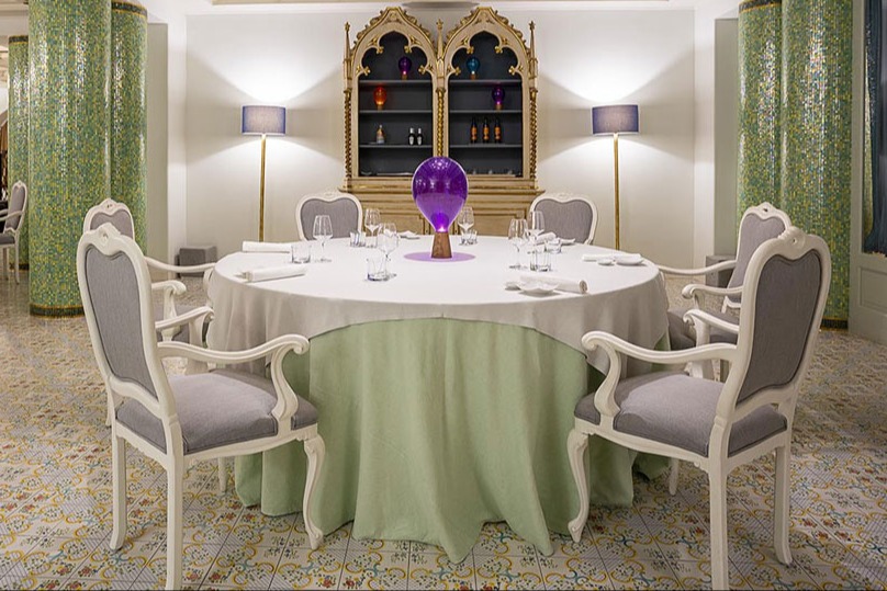 A round table with a green and white covering with six chairs surrounding it