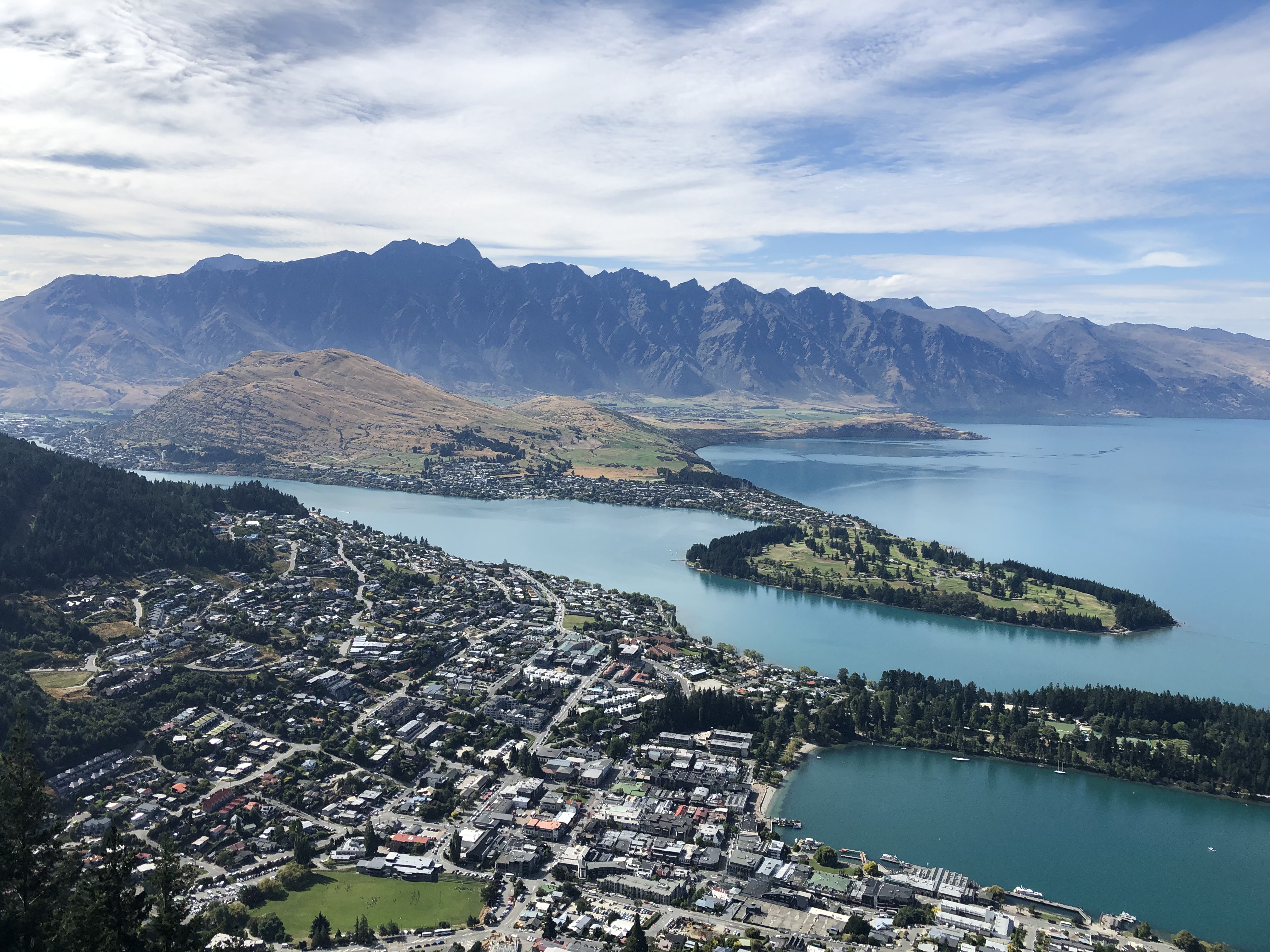 Aerial city view of Queenstown with bodies of water, mountains and city landscape.