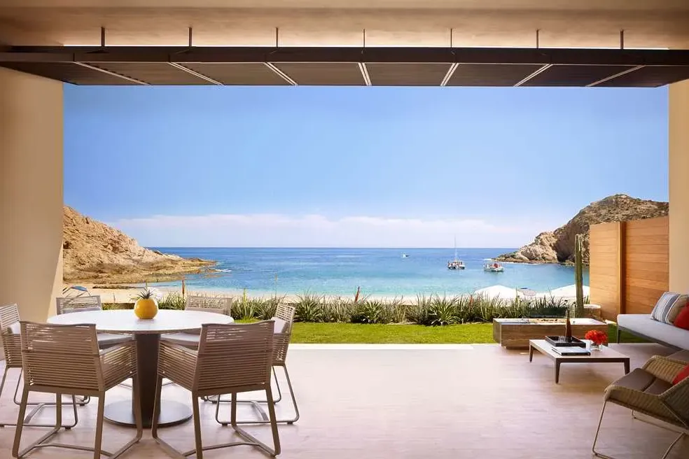 A private table setting and seating area at a private villa with beach views and access. Two boats are moored in a small harbor