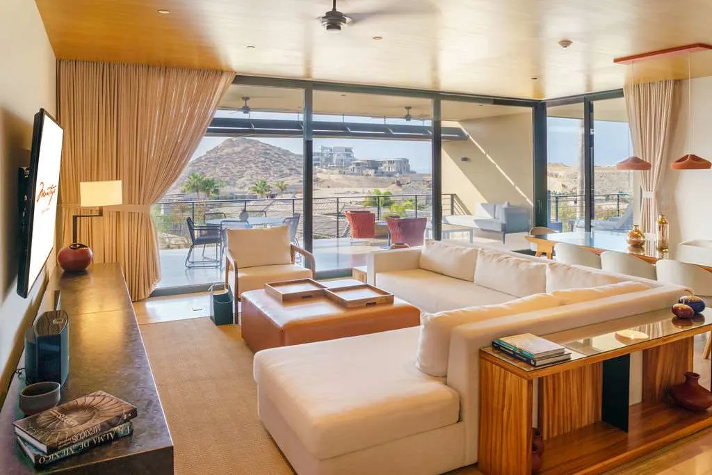 Large sectional sofa and a private dining table in a living room with private loungers and table settings on an attached balcony