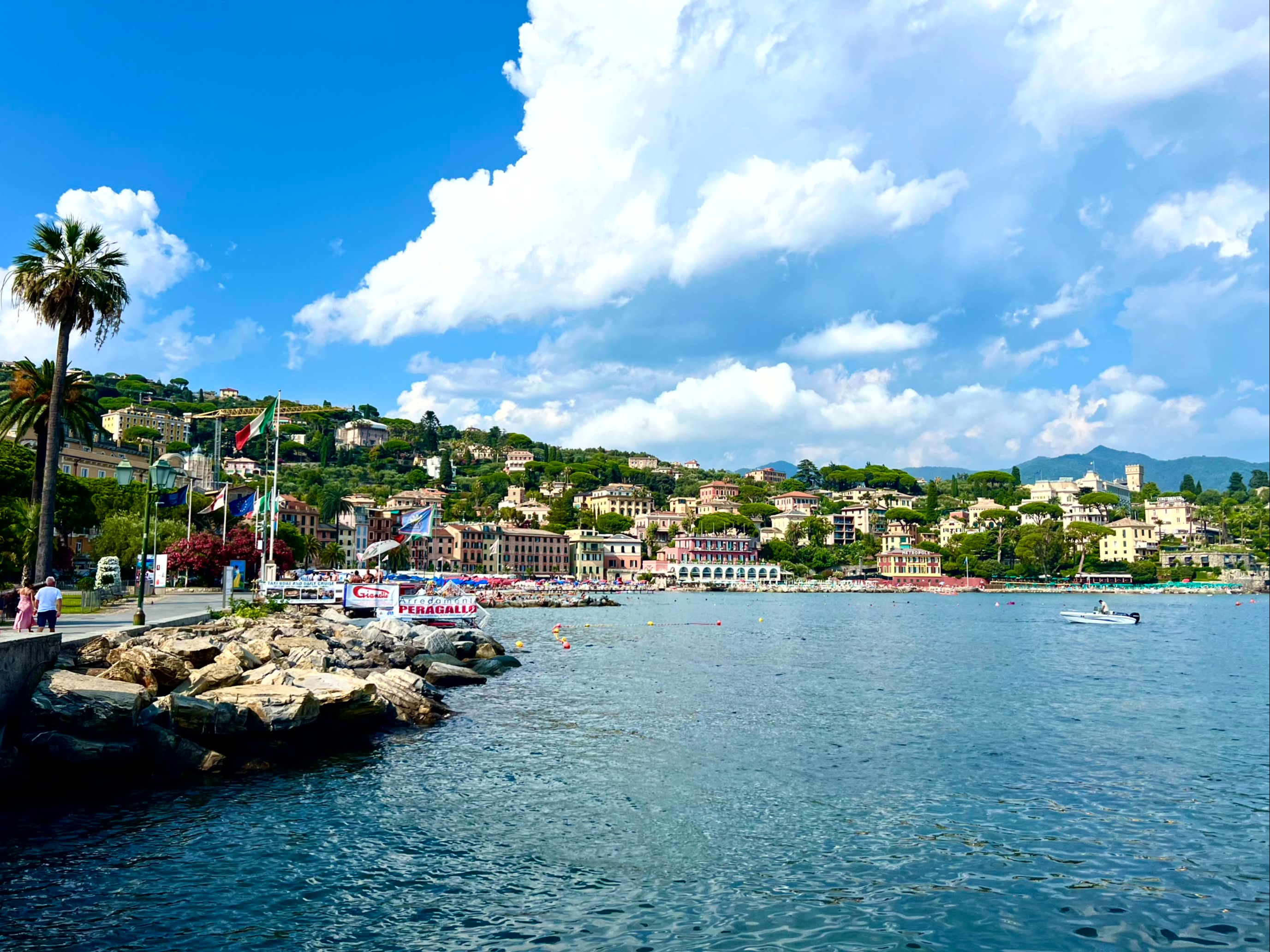 A coastal town with buildings on a hillside and boats floating in the ocean.