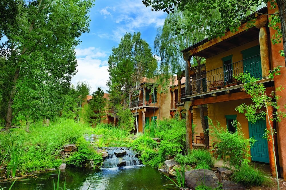Lush vegetation and a small creek in front of the Southwest-inspired architecture of El Monte Sagrado Resort and Spa