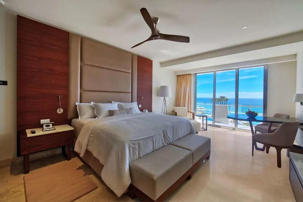 Spacious room with a large bed, simple decor and a great ocean view from an attached balcony