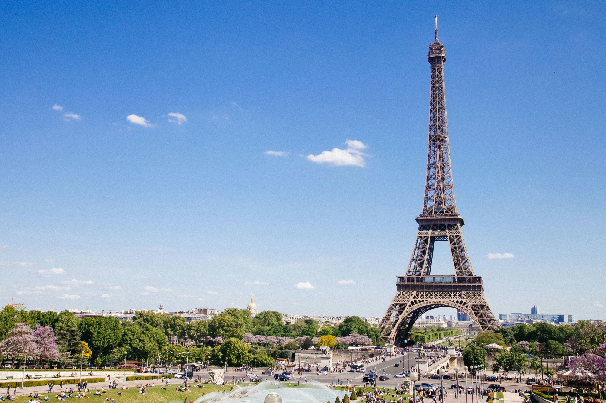 A view of the Eiffel Tower standing against a blue sky dotted with clouds.