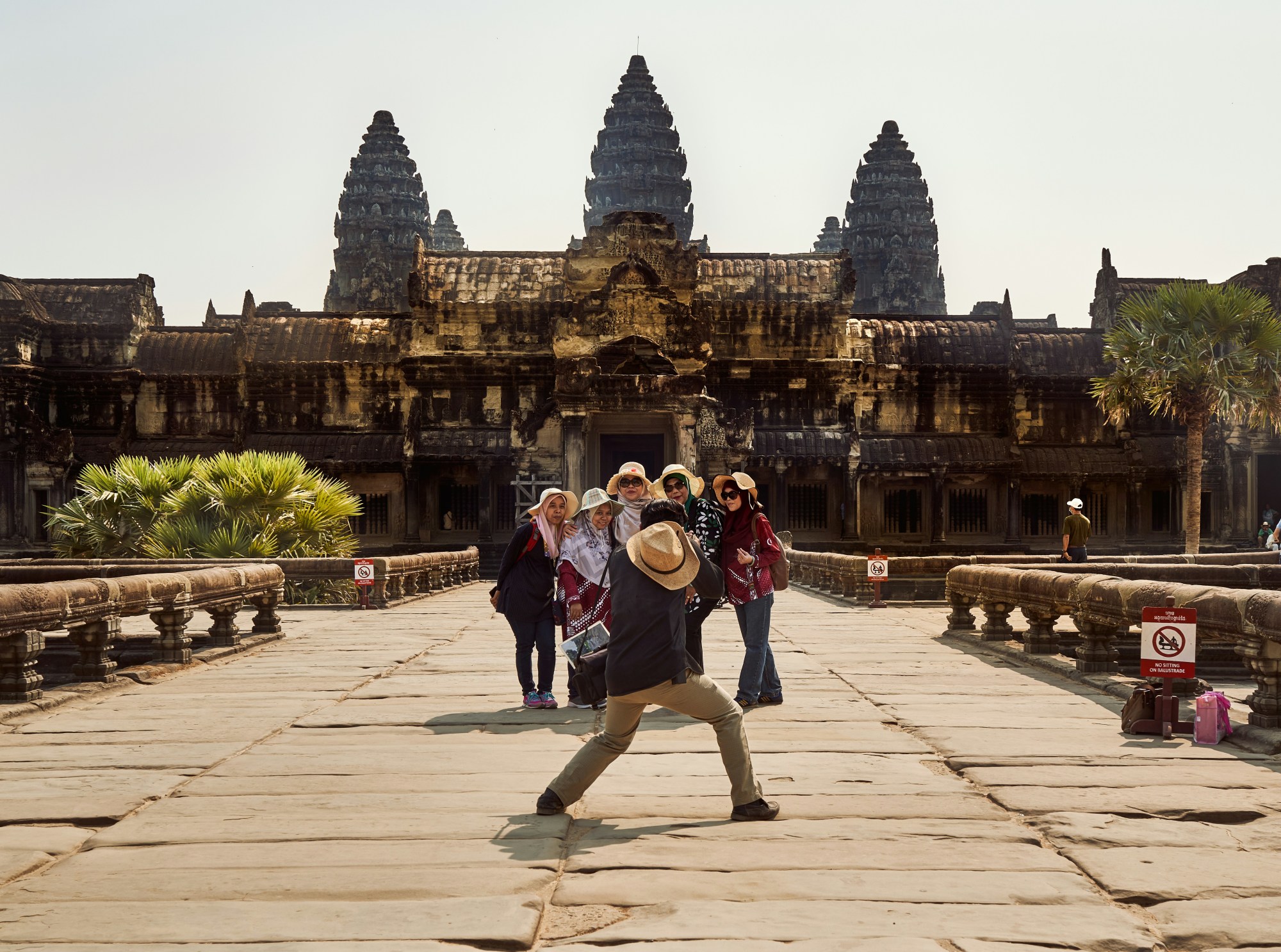 Tourists mill and take photos near a temple on a sunny day.