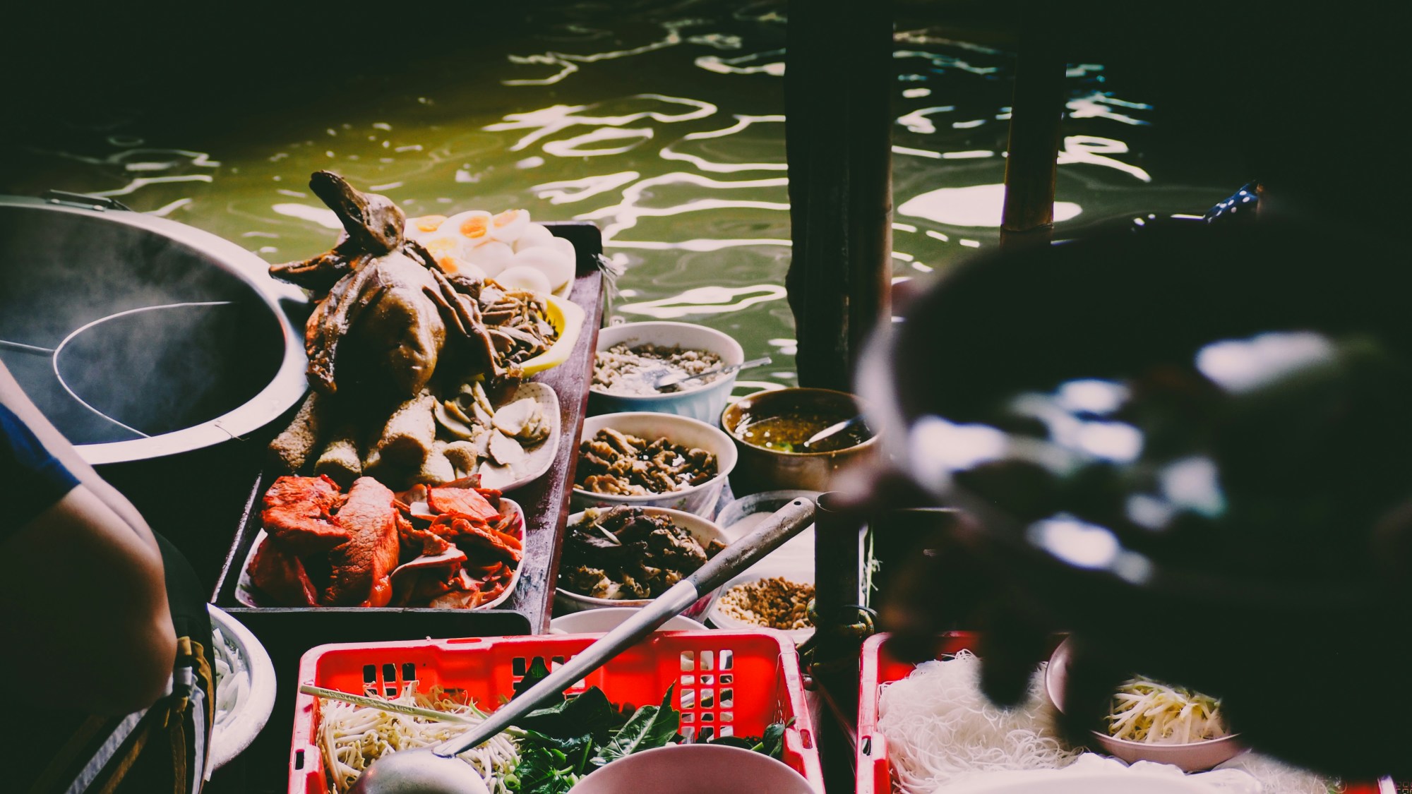 Street food in Bangkok balanced on trays in pots on a sunny day.