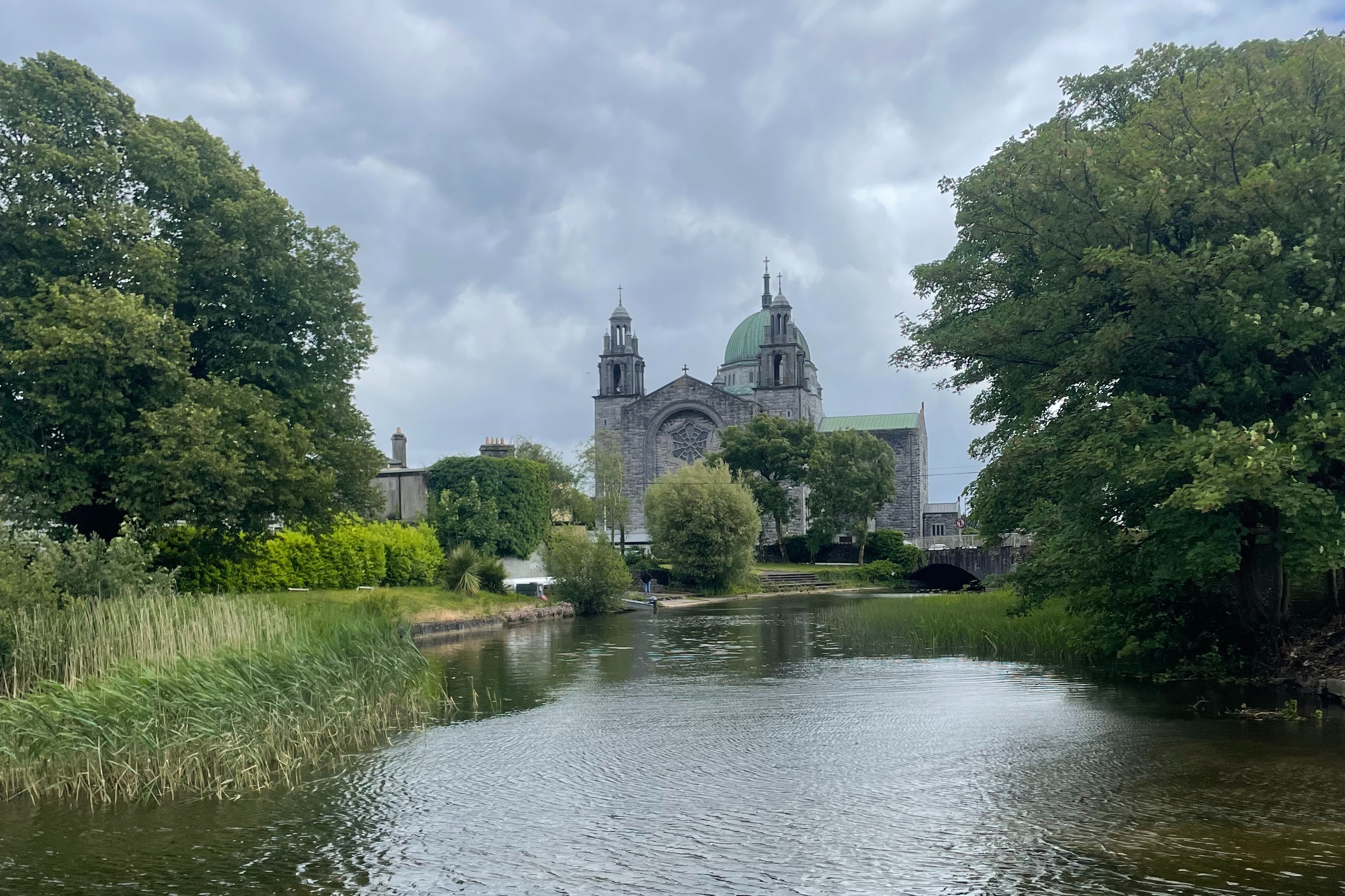 A cathedral sitting behind a small pond surrounded by large trees